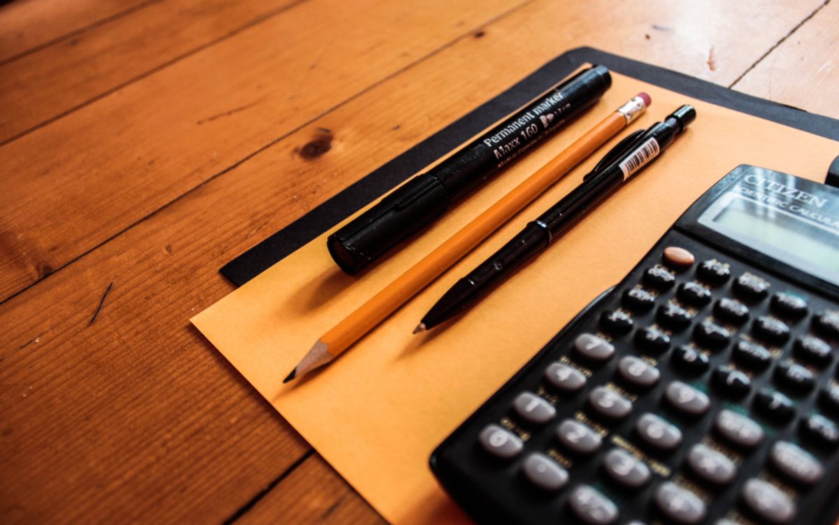 Calculatrice, crayons et enveloppe posés sur un bureau en bois
