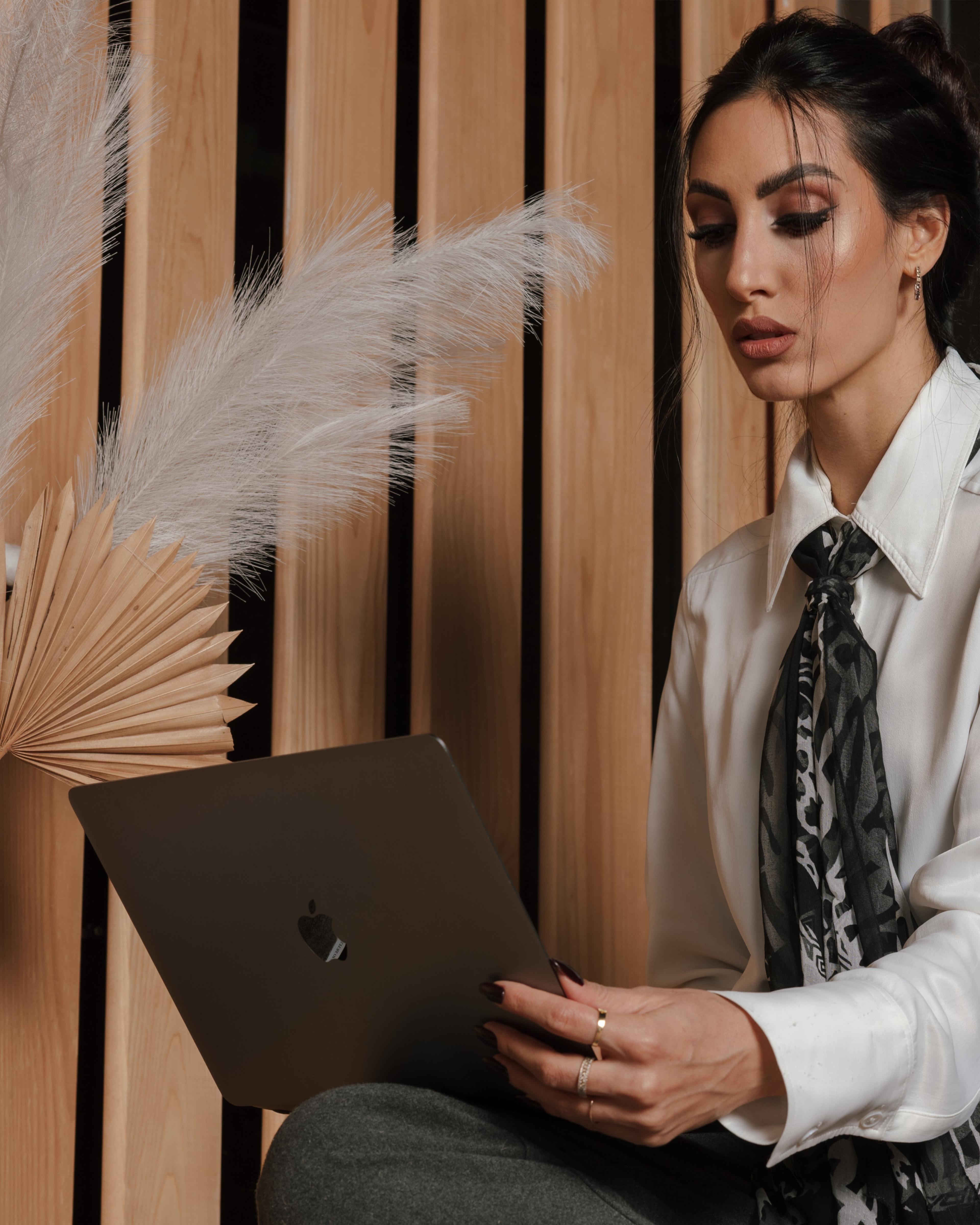 Gala Isidora radi na laptopu, u pozadini drvene letvice i pampas trava