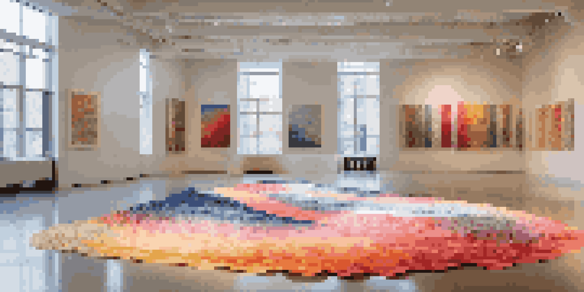 An installation art piece made of recycled fabric, creating waves of color in a bright gallery with sunlight filtering through windows.