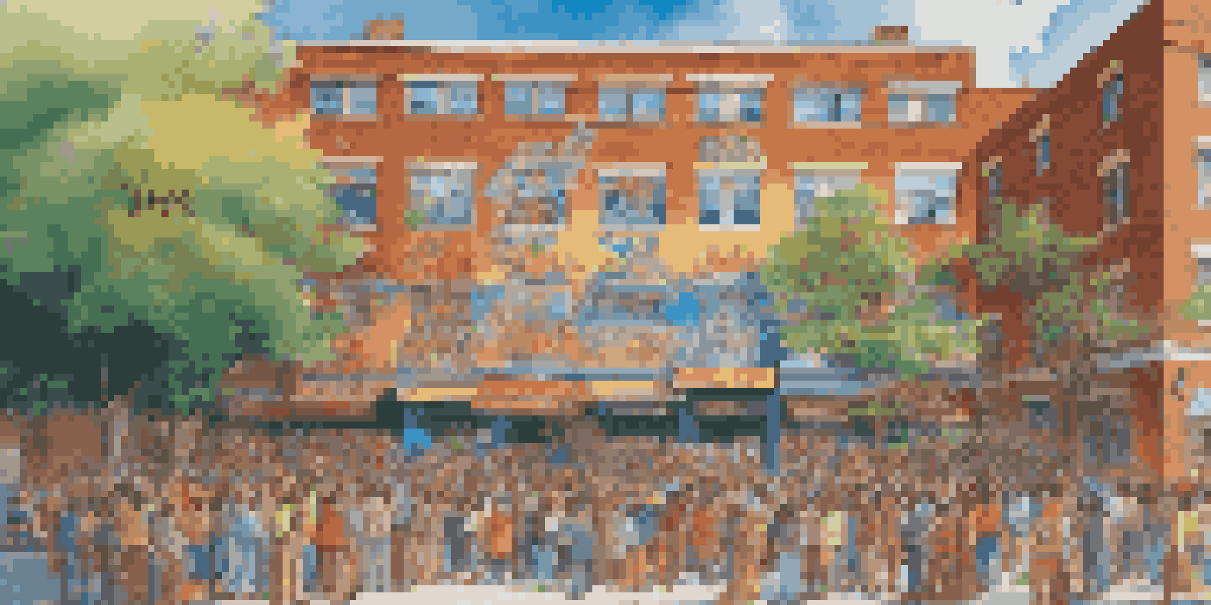 A colorful mural depicting diverse community members engaged in traditional activities on a brick building in an urban setting.