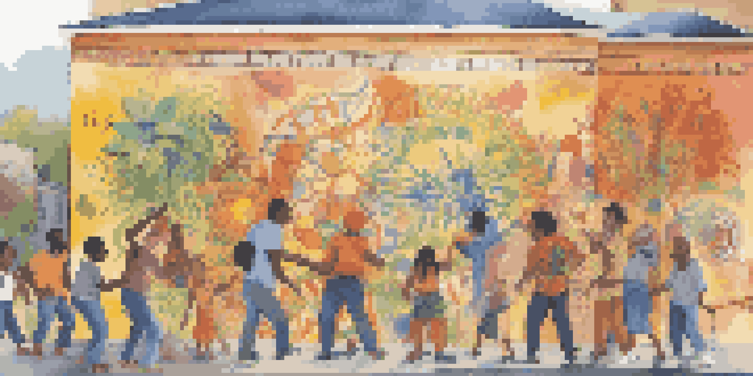 A colorful community mural with diverse individuals collaborating on the artwork under bright sunlight.