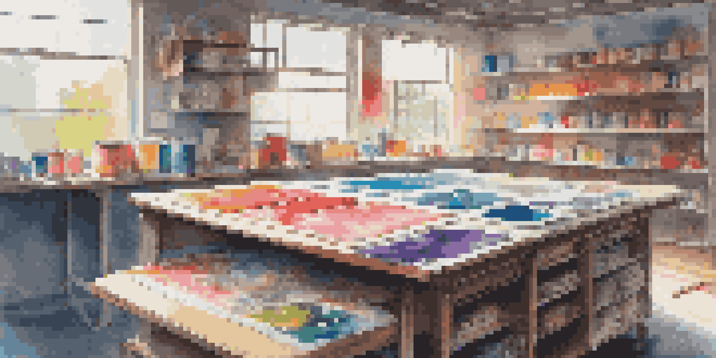 A colorful screen printing workspace with inks, squeegee, and printed fabrics under soft natural light.