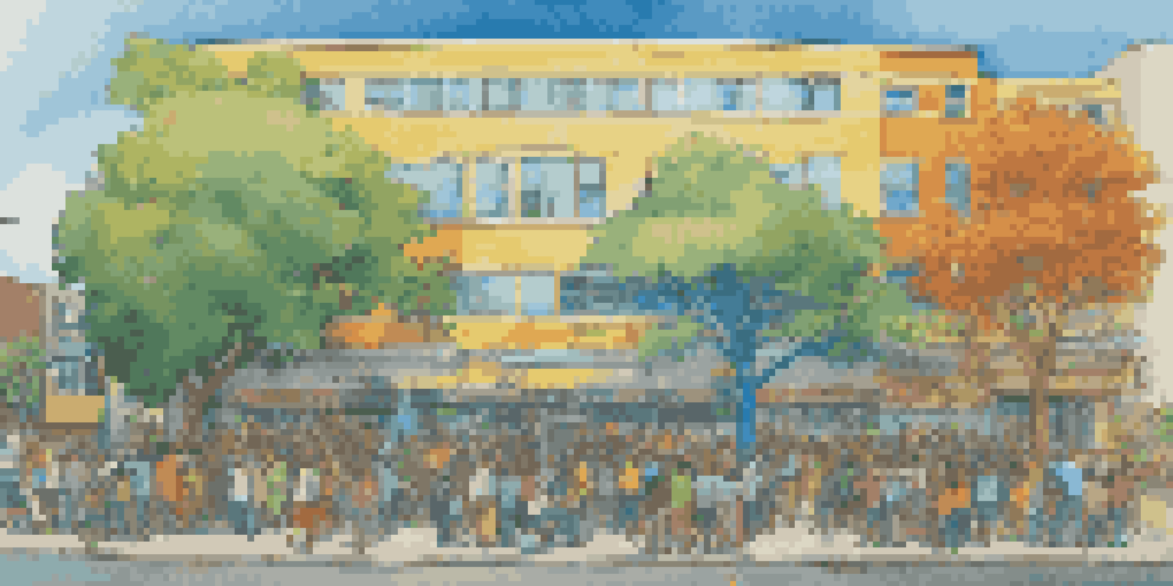 A colorful community mural featuring trees, animals, and ocean waves, with diverse individuals painting together in front of a building.