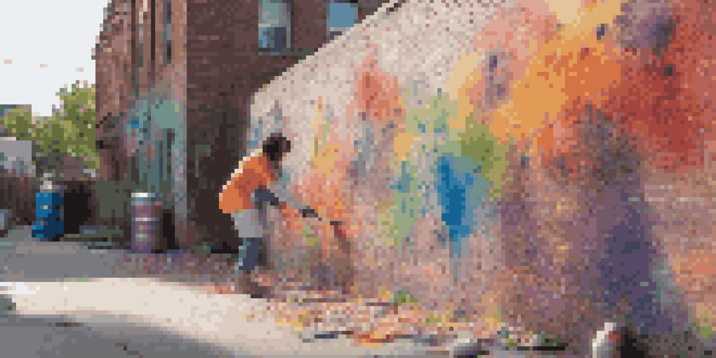 A young artist painting a colorful street art mural on a brick wall, with paint cans scattered around and sunlight casting shadows.