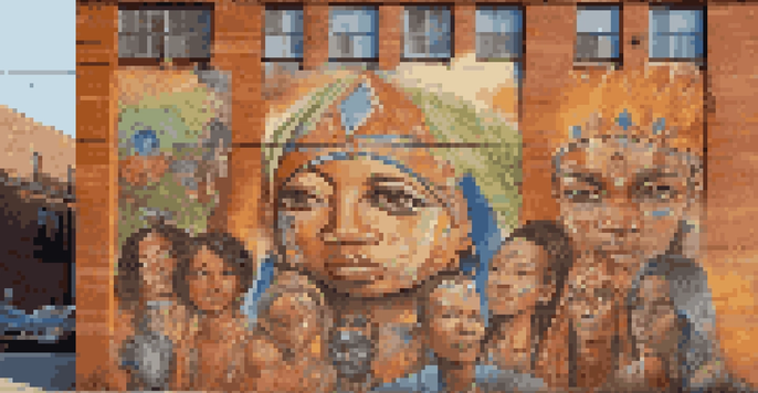 A colorful mural depicting diverse faces and cultural symbols on a brick wall, illuminated by sunlight.