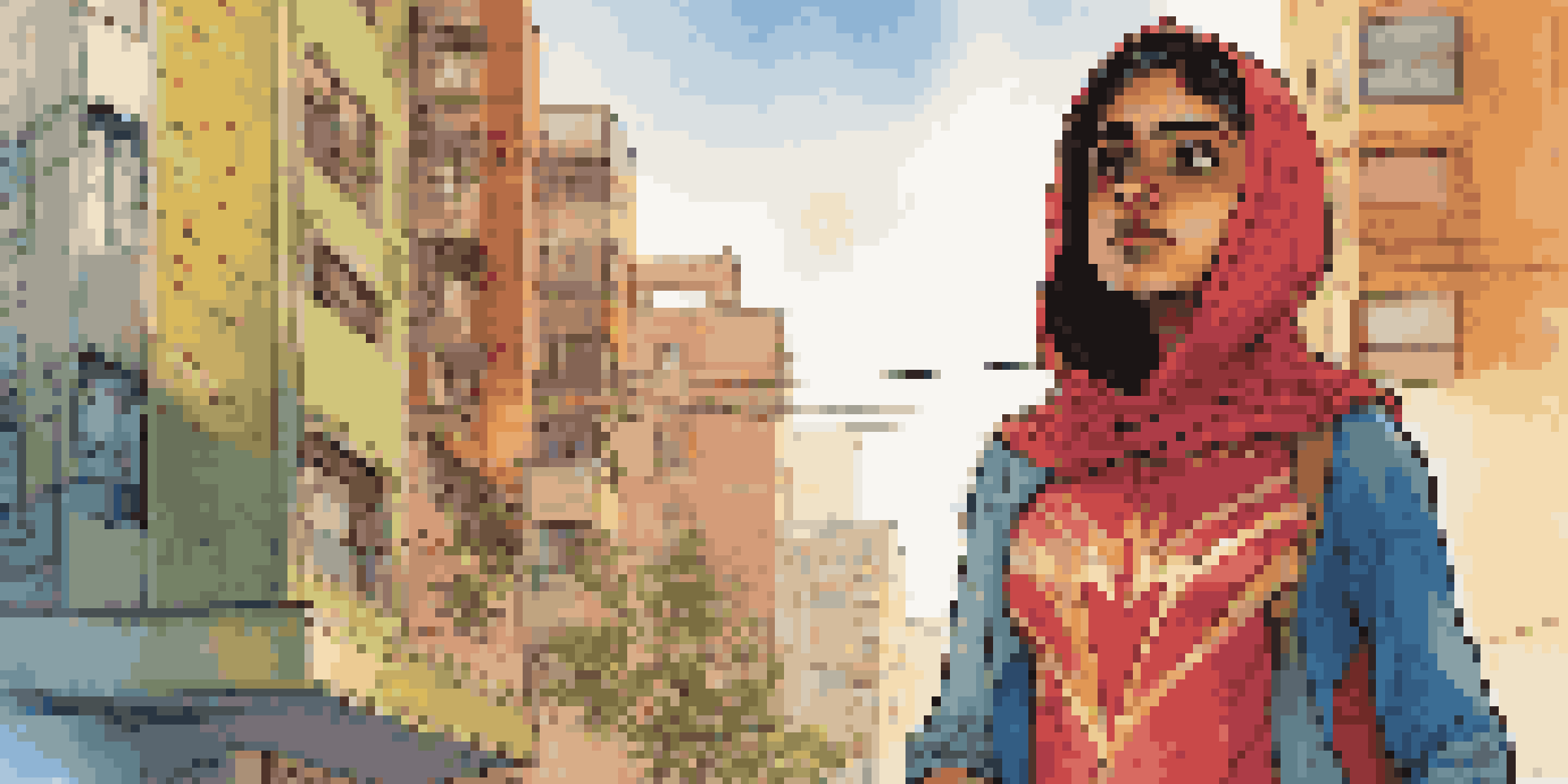 A teenage girl of Pakistani descent in a colorful superhero costume stands confidently in an urban setting with diverse architecture and street art in the background.