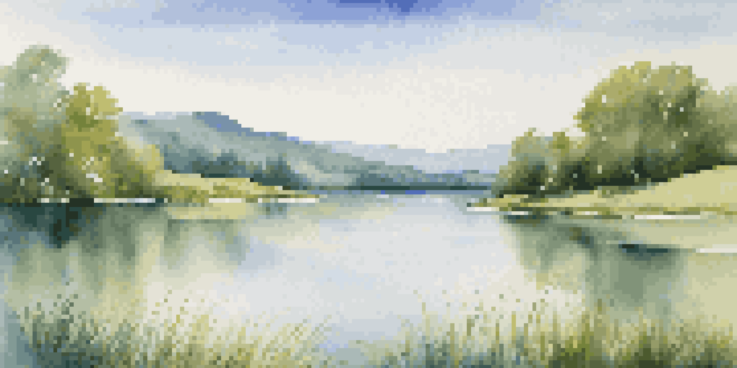 A calm lake with green hills and a clear blue sky, reflecting nature's colors.