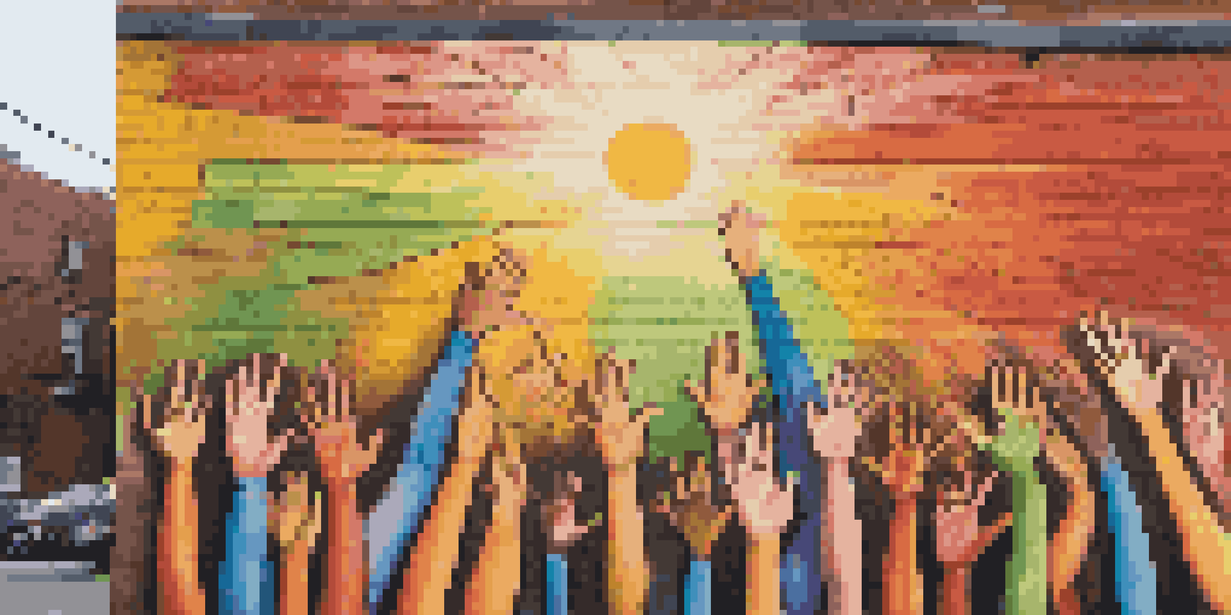 A colorful mural of diverse hands raised together in solidarity, located on a city wall, with sunlight illuminating the scene.