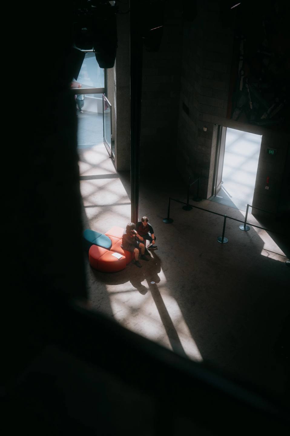 A seated visitor illuminated by a narrow shaft of light.