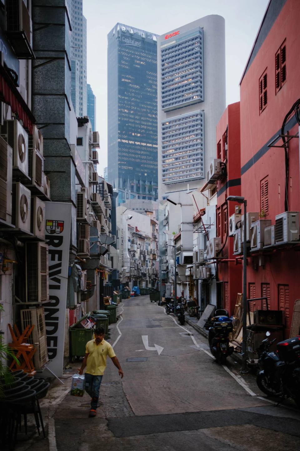 Colourful shophouses beneath a tall modern building.