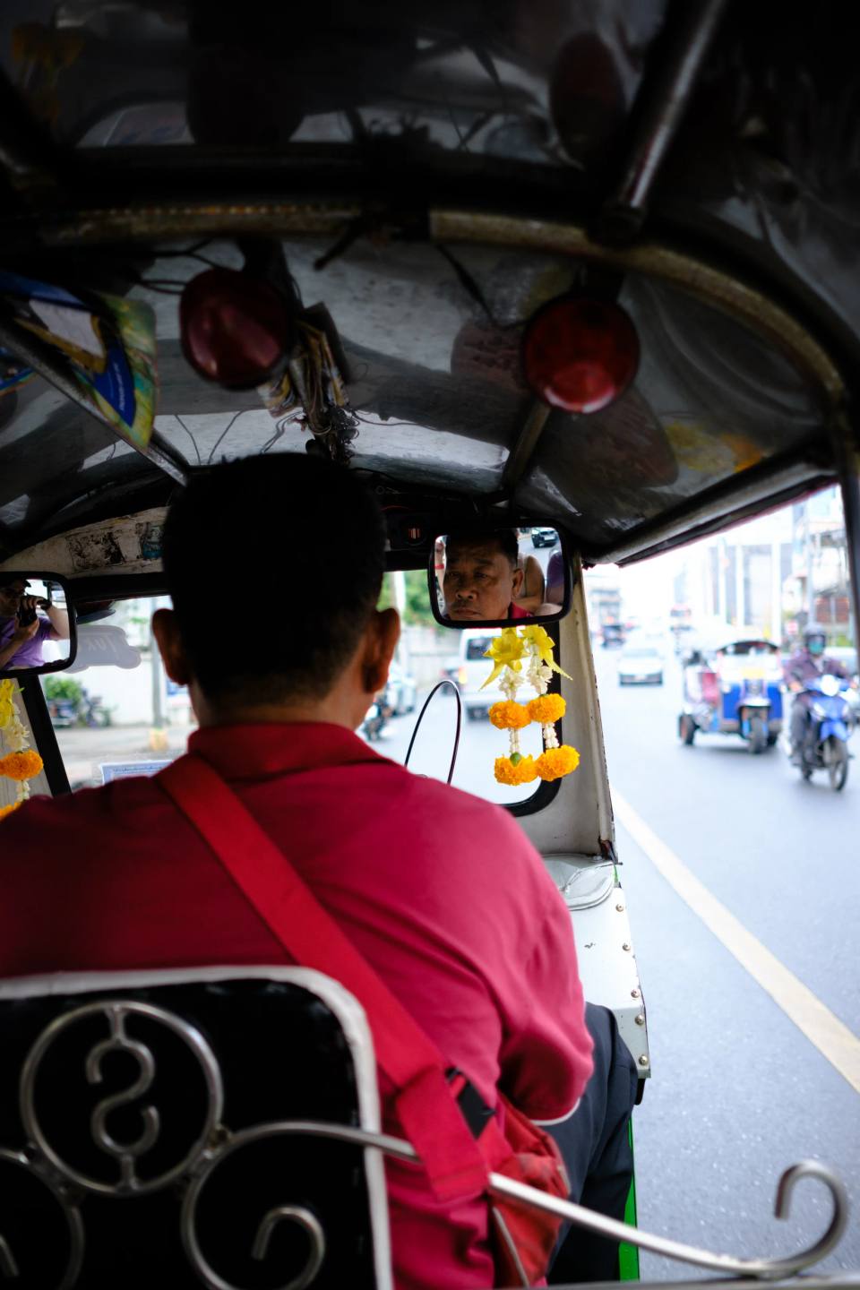 A view from behind a driver wearing a red shirt.