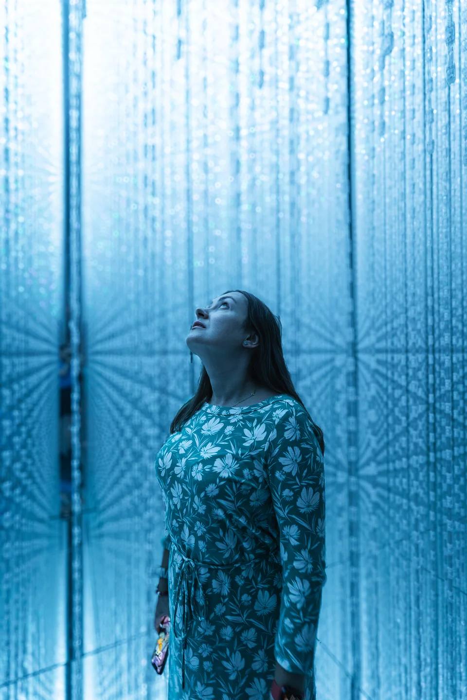 A person looking upwards in a blue illuminated installation.