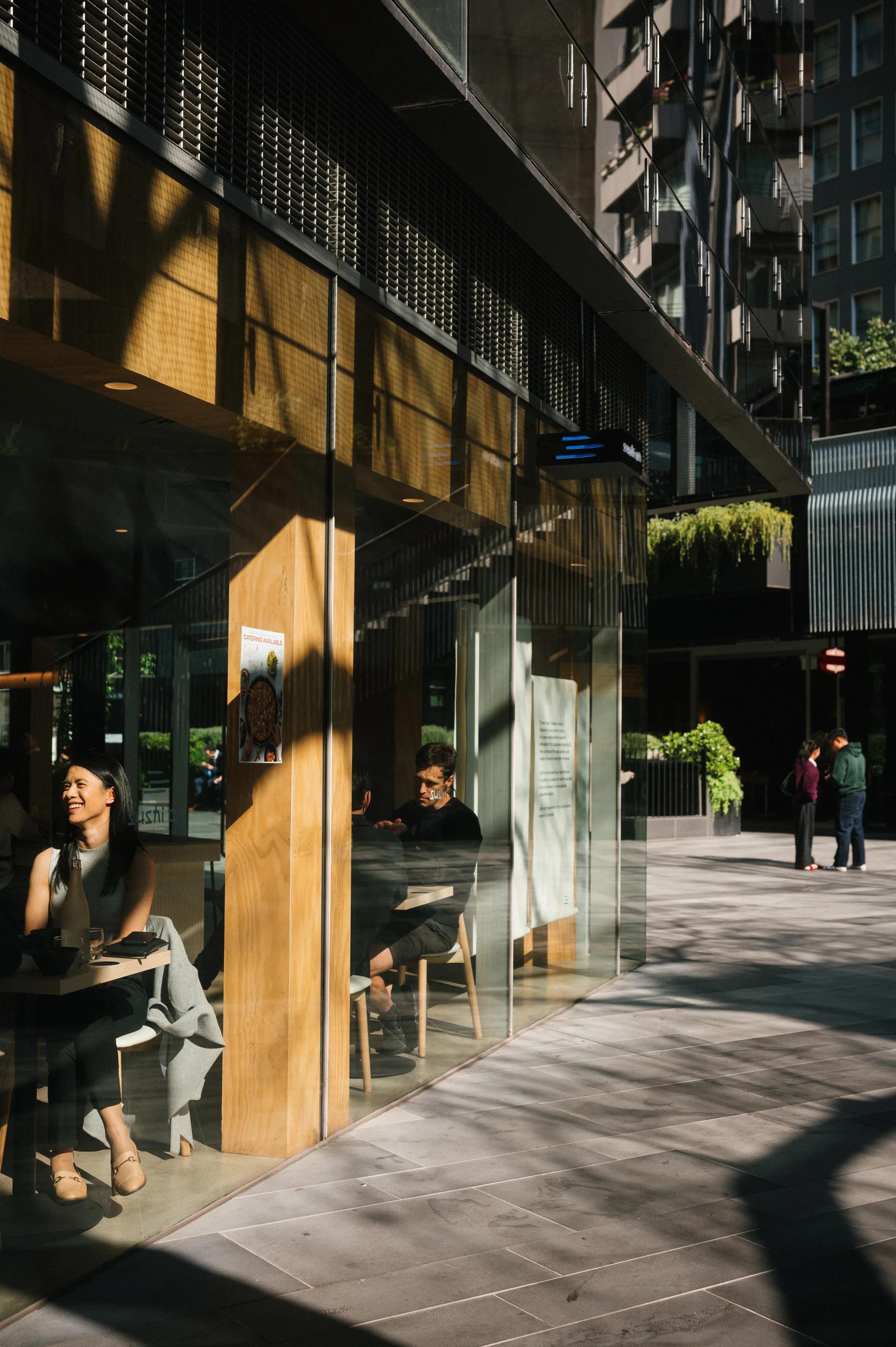 Warm sunlight and long shadows outside a city cafe.