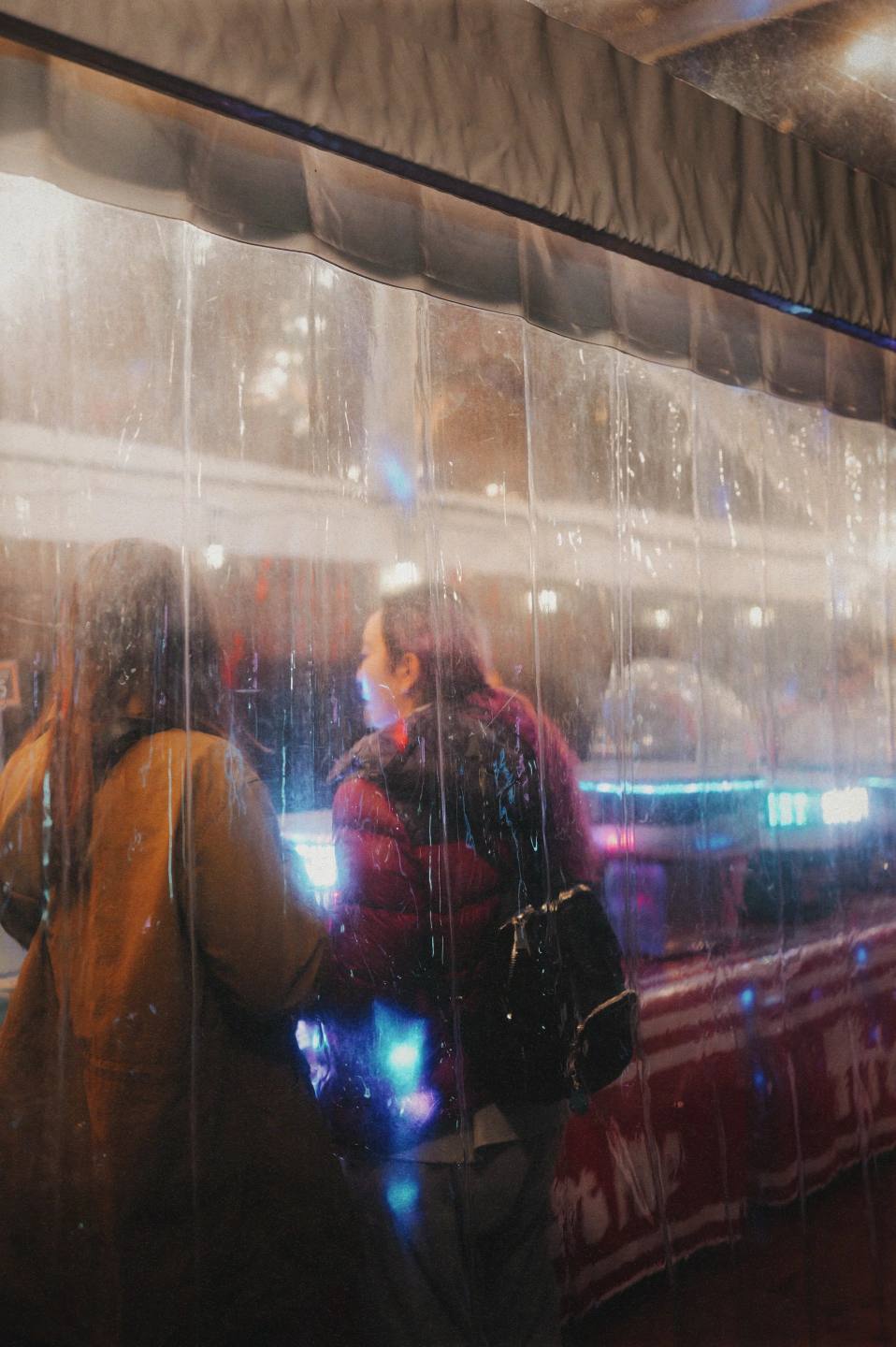 Figures and lights layered through reflections in glass.