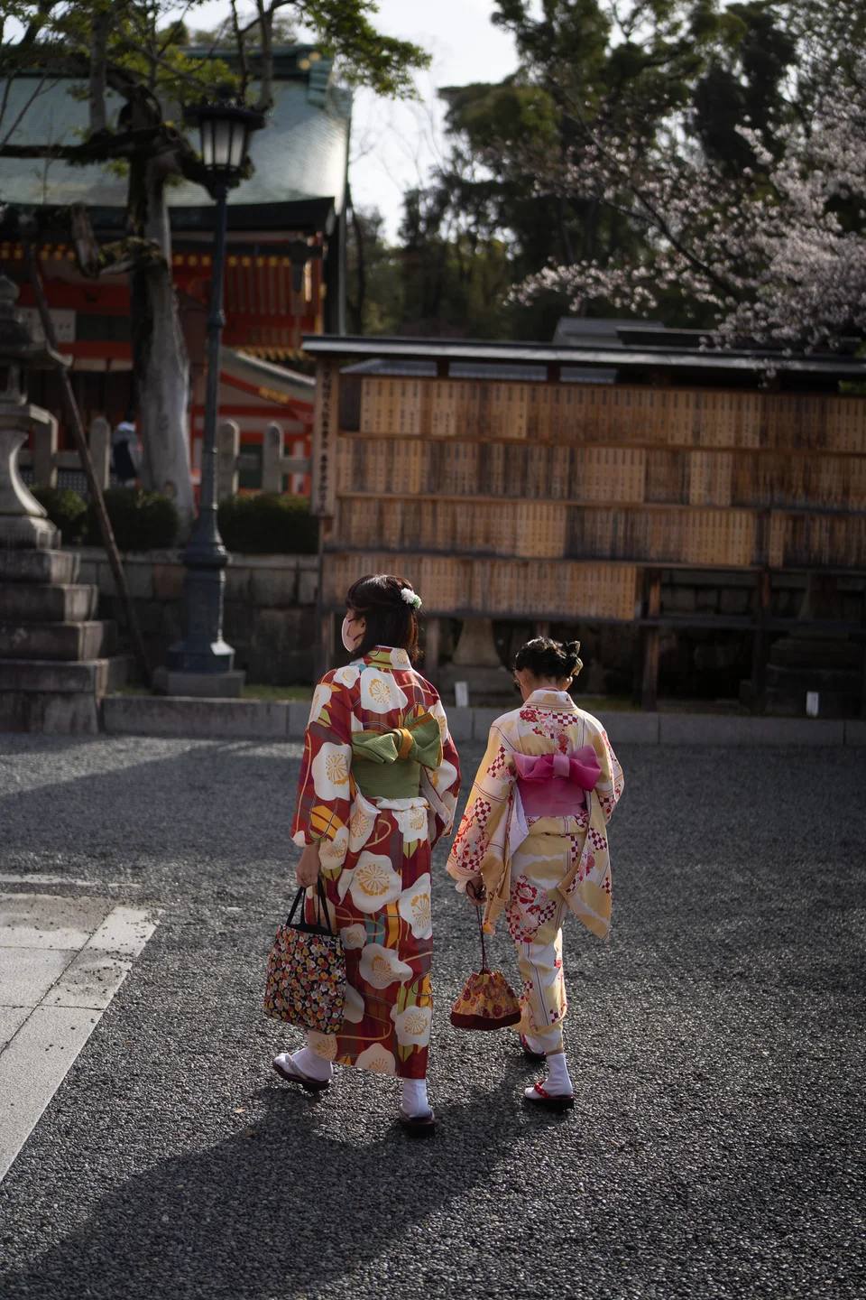 Two people in colourful kimono walking towards a shrine.