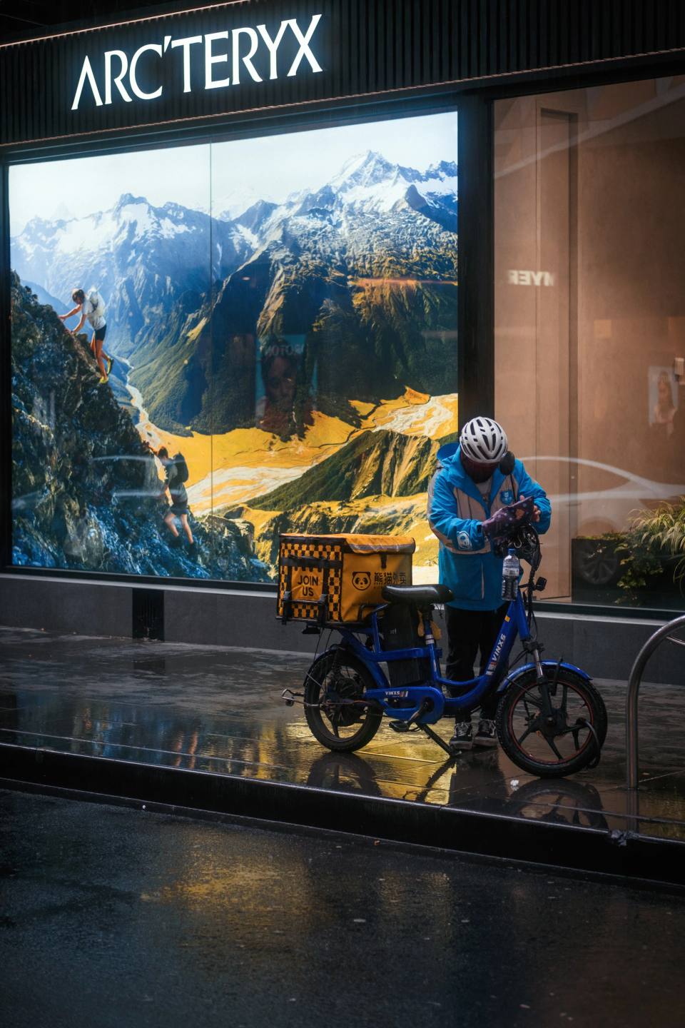 A cyclist passing an illuminated shop window at night.