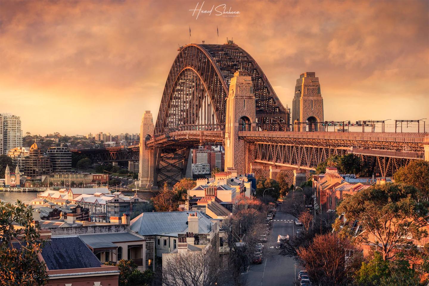 Sydney Harbour Bridge above waterside buildings beneath a warm evening sky.