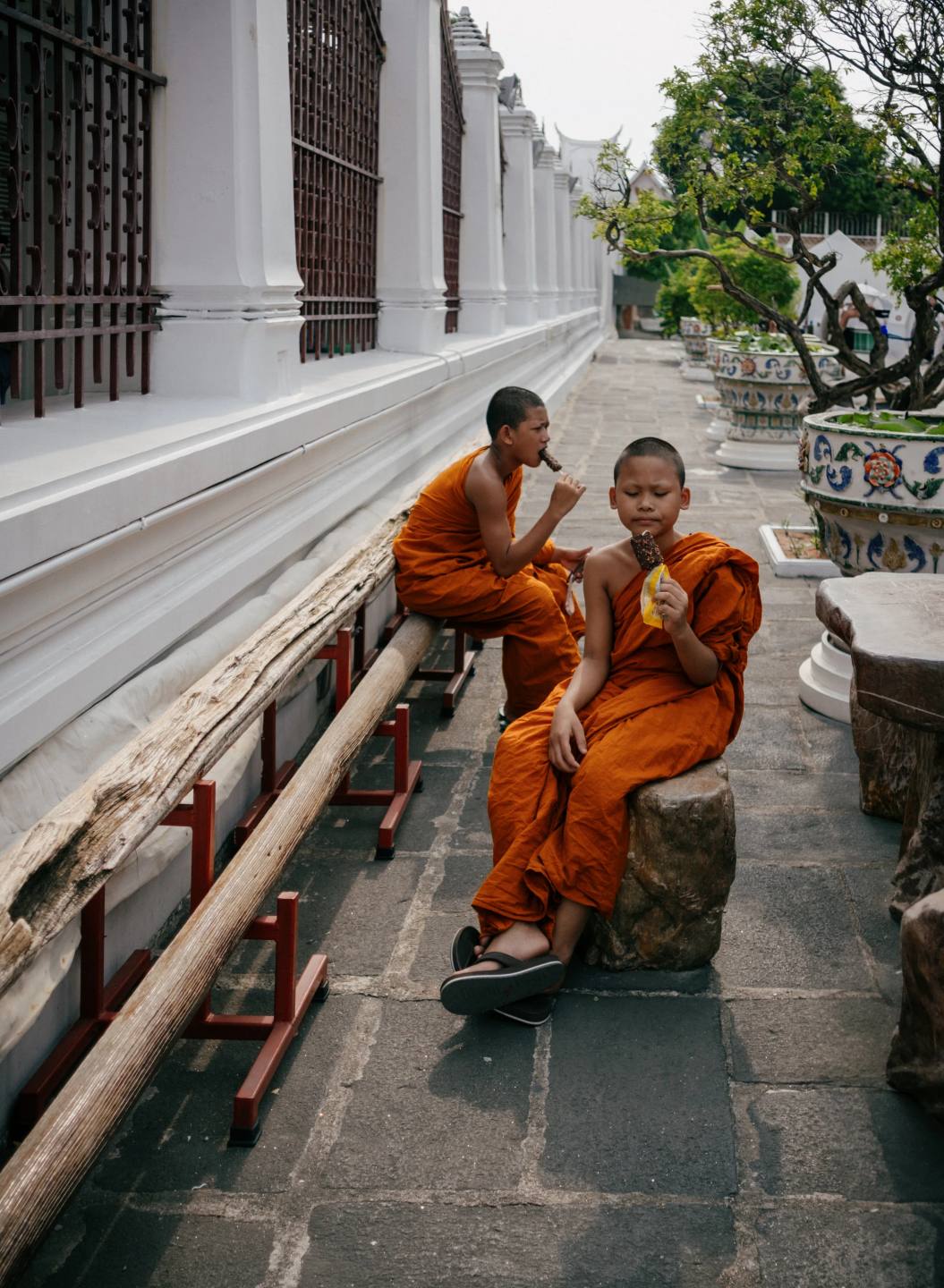 Two monks seated beside a temple wall.