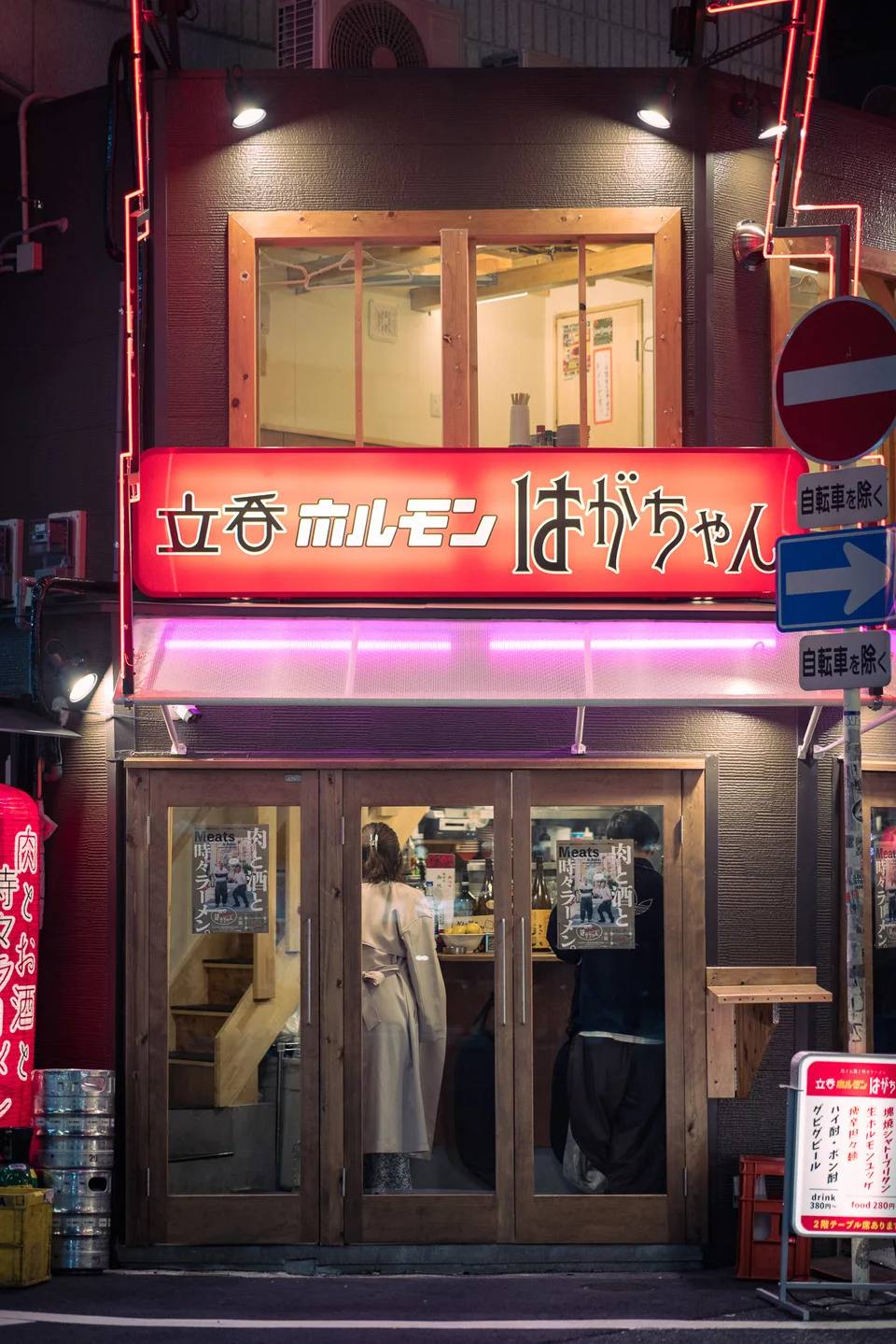 A narrow multi-storey restaurant facade illuminated at night.