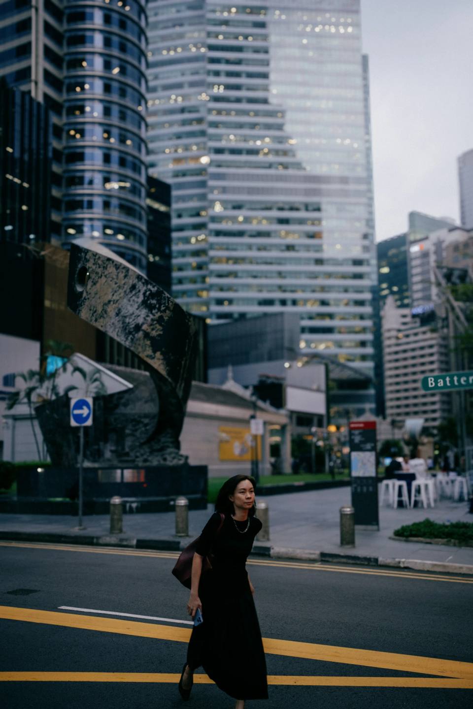 A pedestrian crossing a street between high-rise buildings.