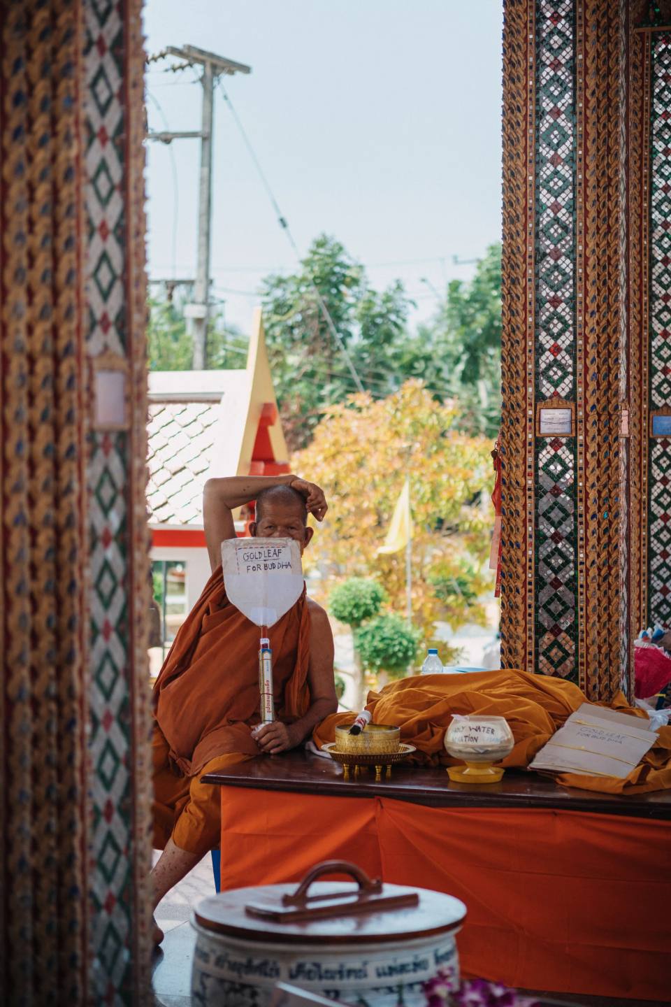 A monk seated beside offerings inside a temple.