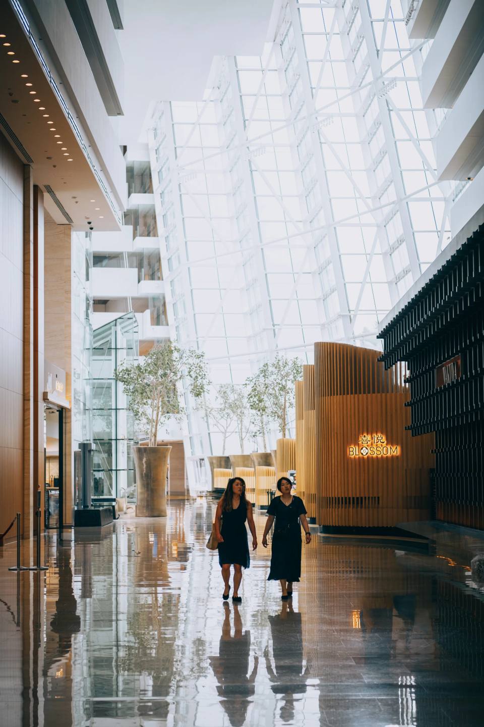 Two people walking through a bright glass atrium.