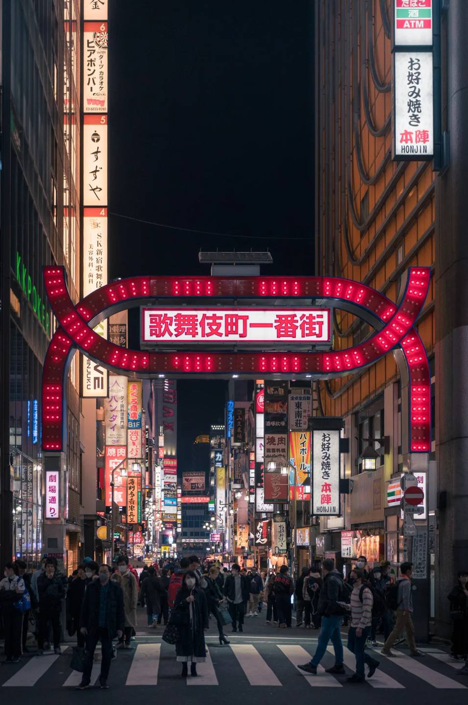 A brightly lit gateway above a busy city street at night.