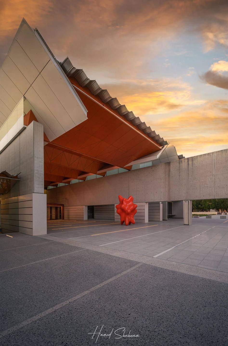 An angular canopy and red sculpture outside the National Portrait Gallery at sunset.