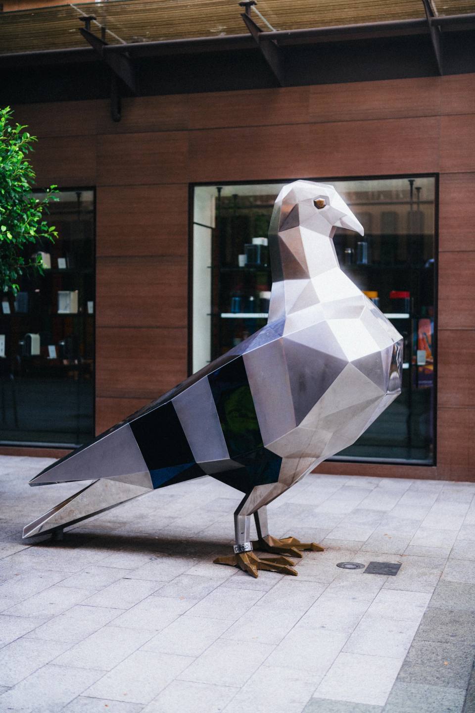 A geometric pigeon sculpture on a city pavement.