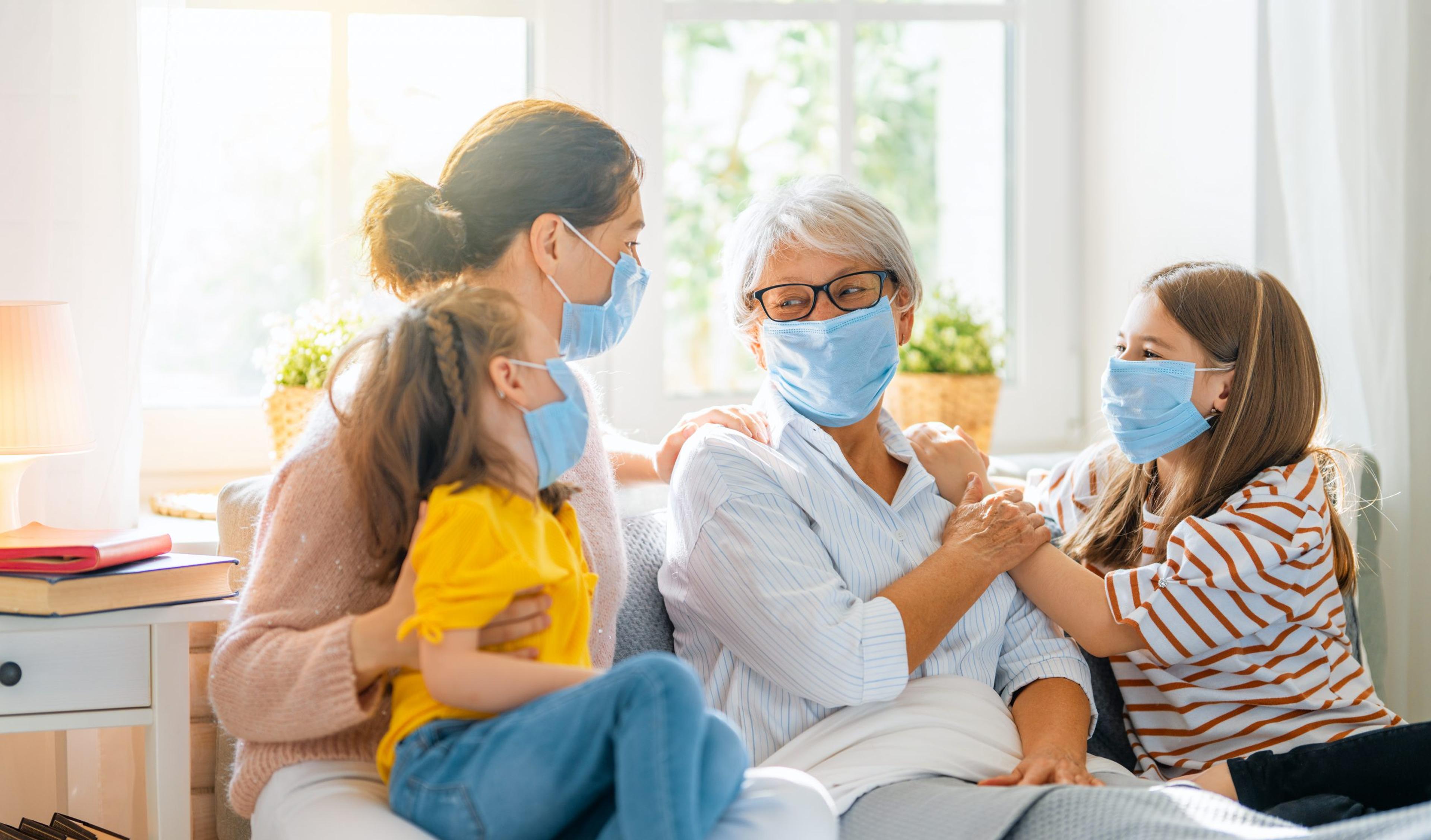 Grandmother visiting with her daughter and grandchildren, all wearing masks