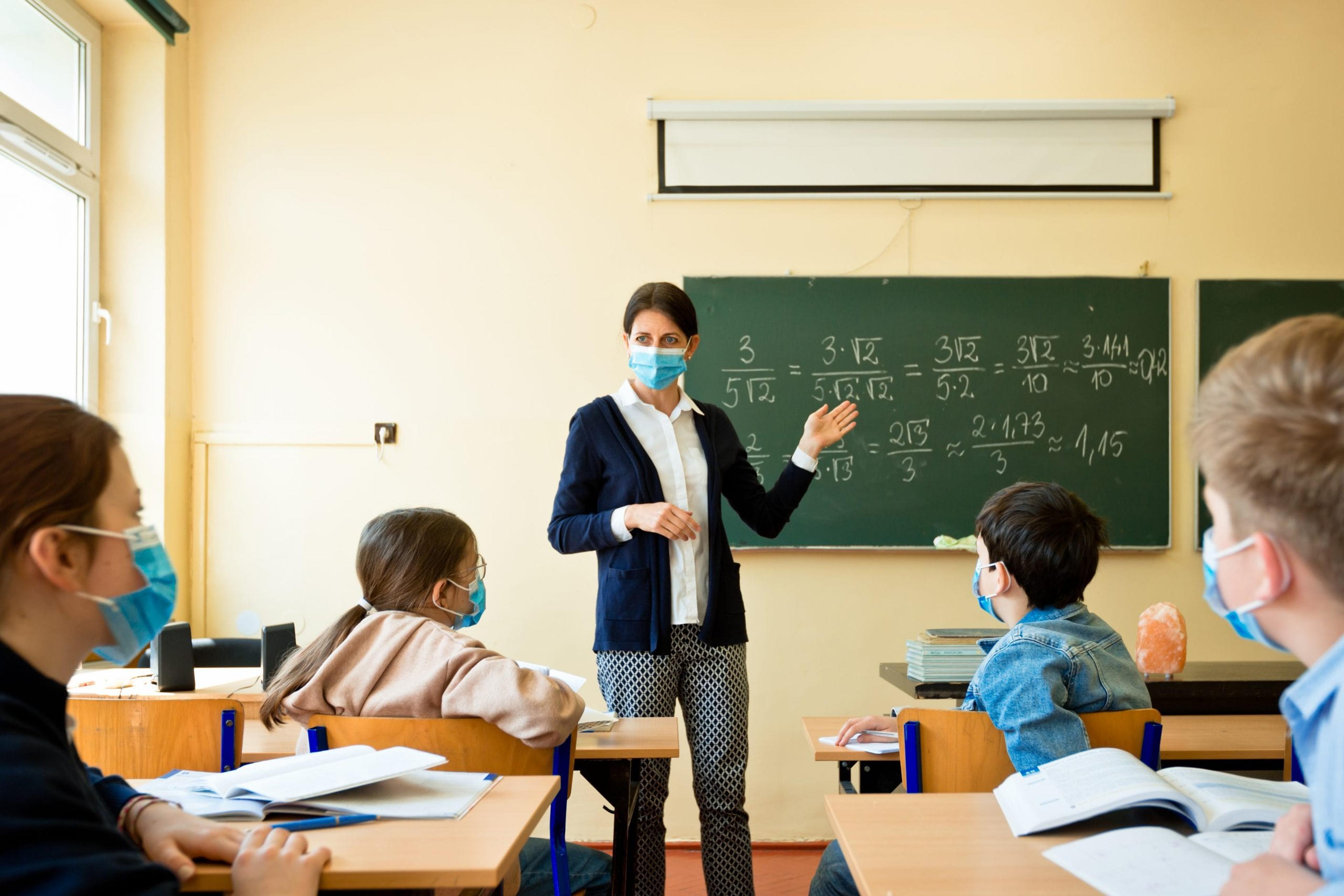 Teacher standing in front of class wearing a mask
