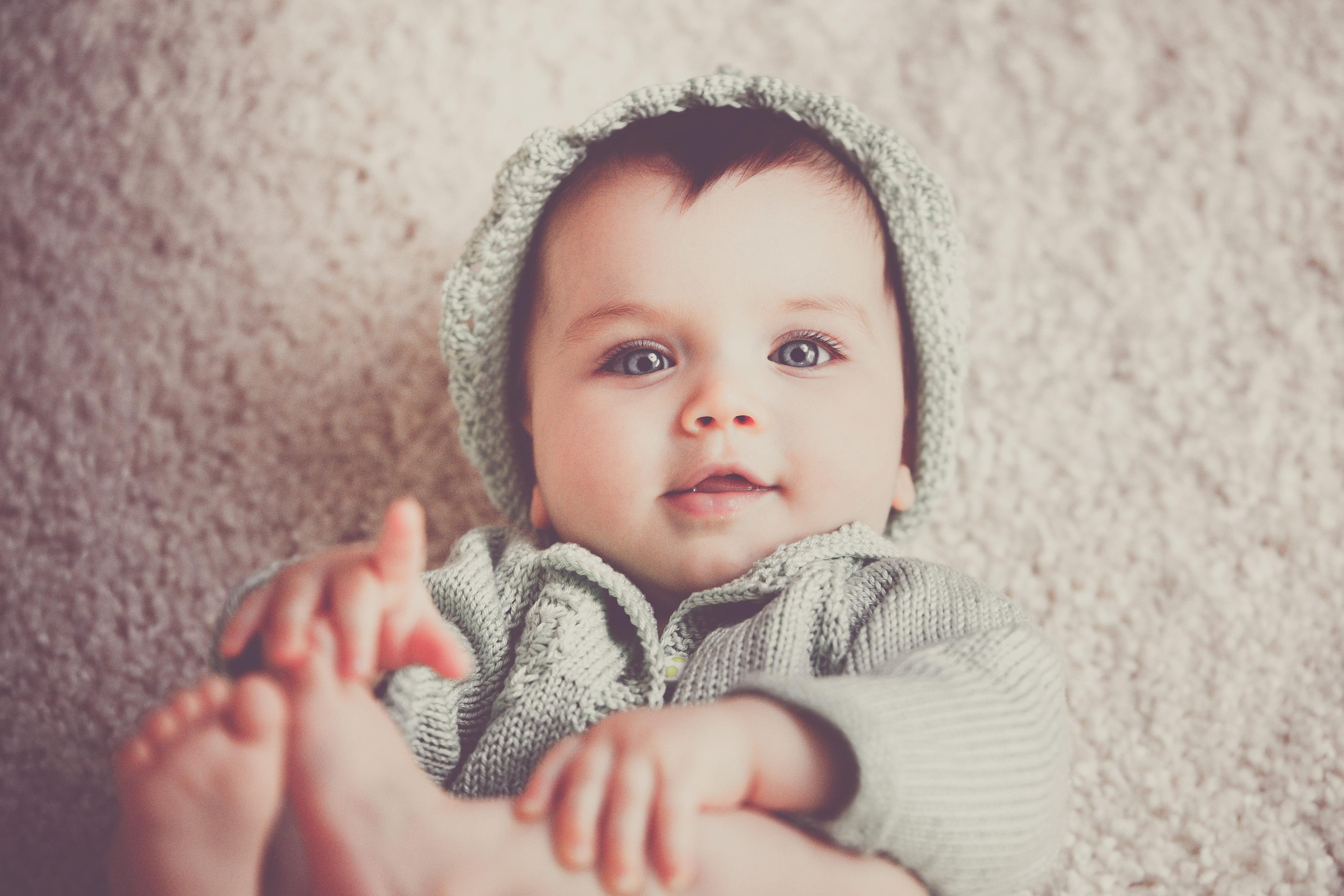 closeup of a baby smiling and holding their foot.
