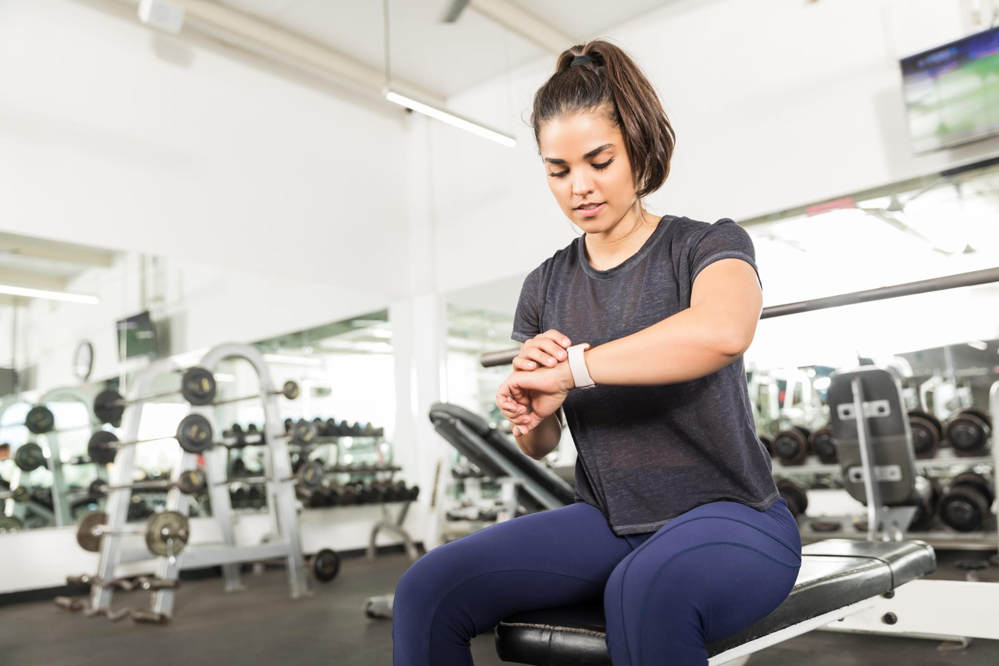 Sporty Female Checking Fitness Activity On Smart Watch In Gym