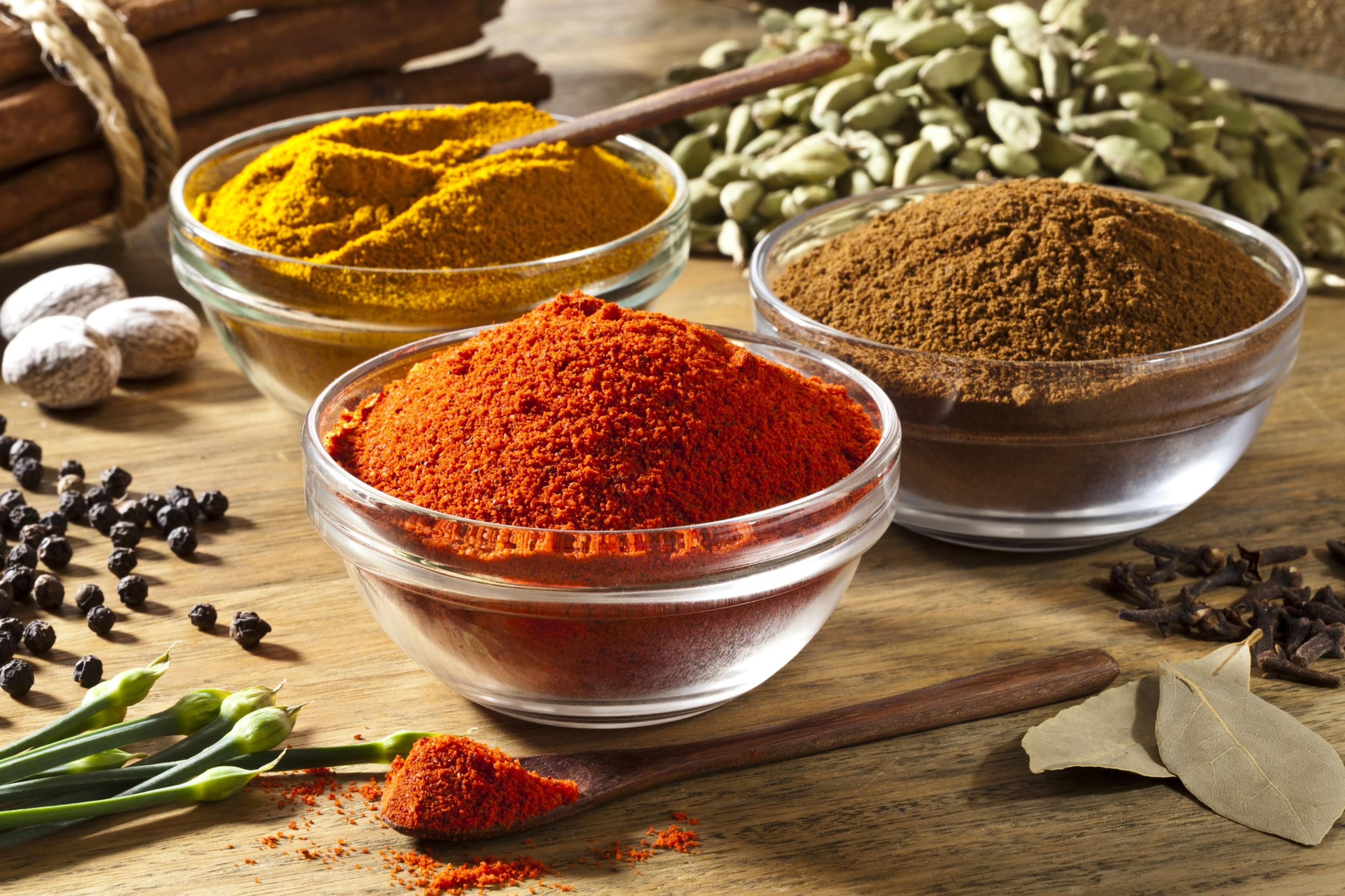 Three bowls filled with spices on rustic wood table