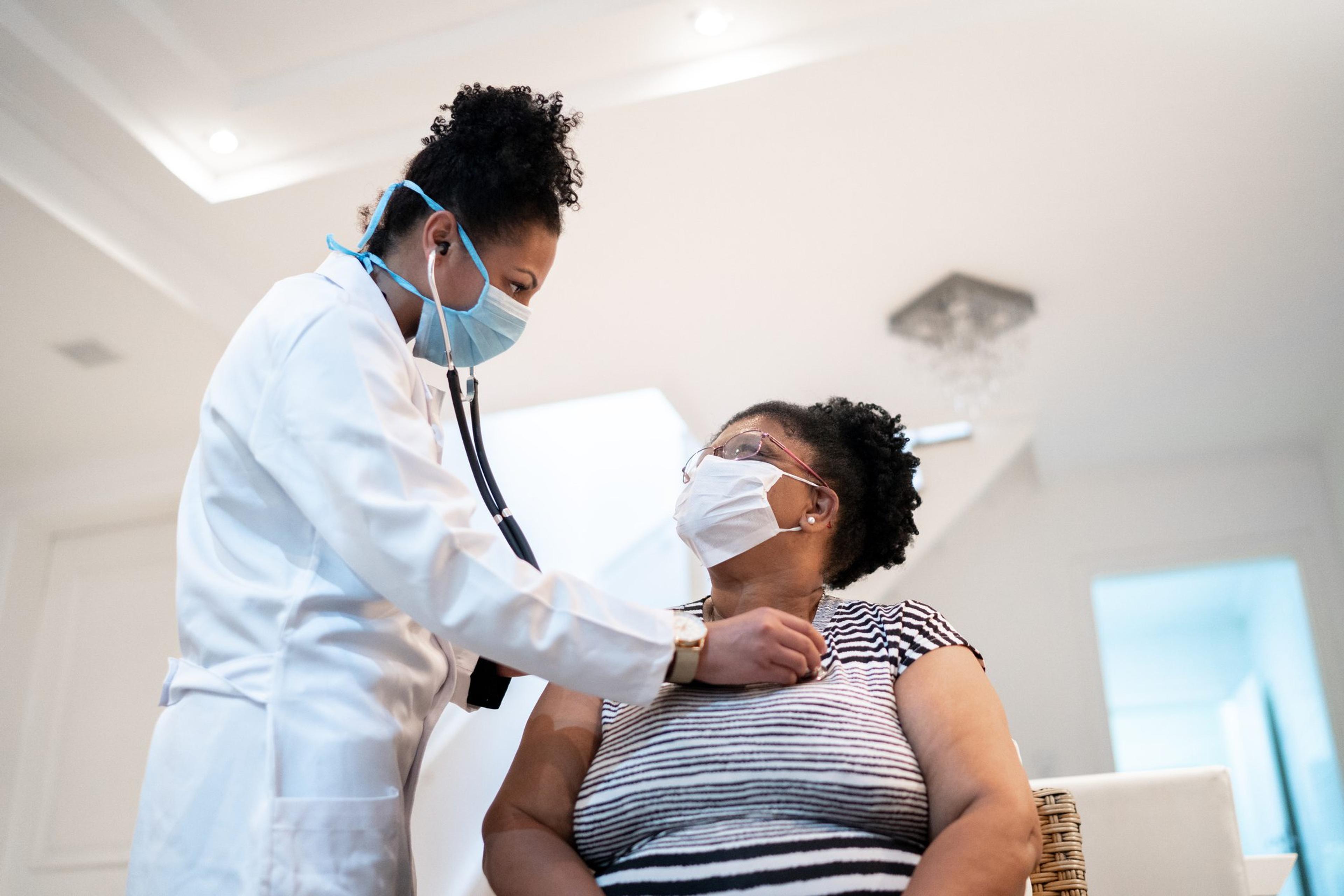 Doctor wearing a mask checks a patient's heartbeat to ensure her heart is healthy