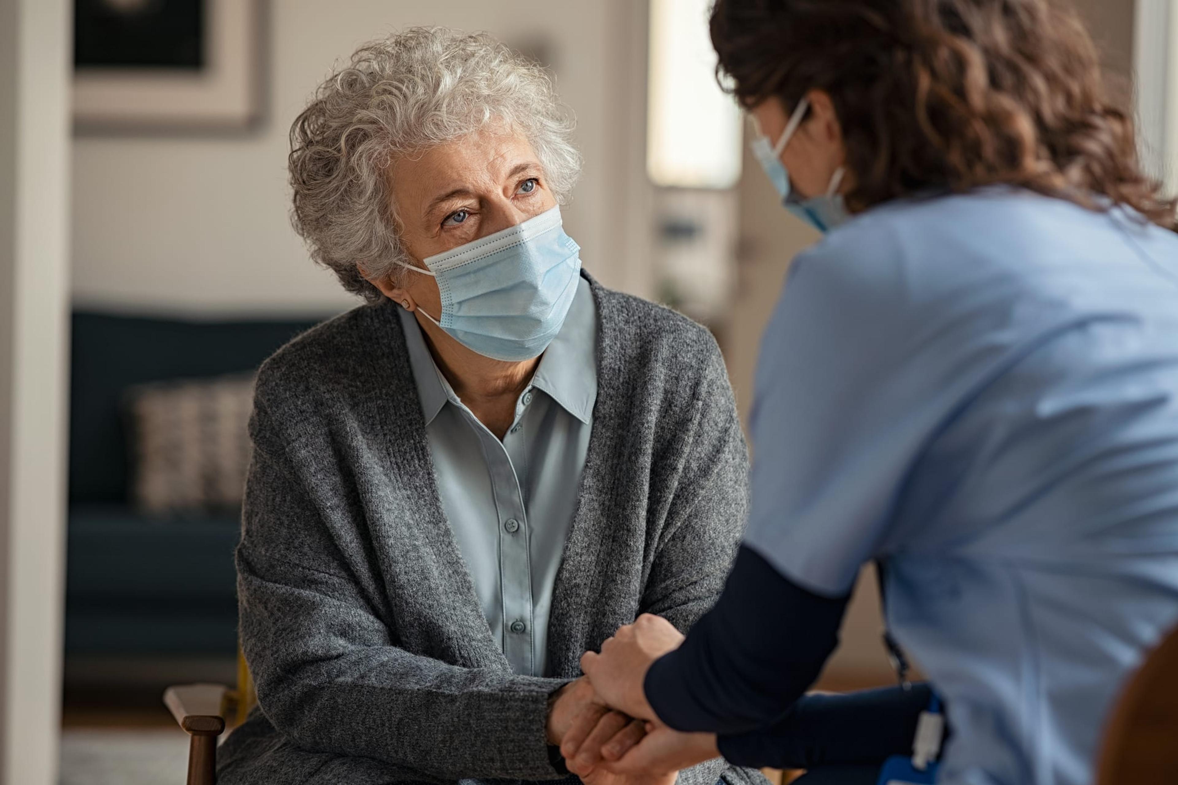Home health care worker consoles an older woman
