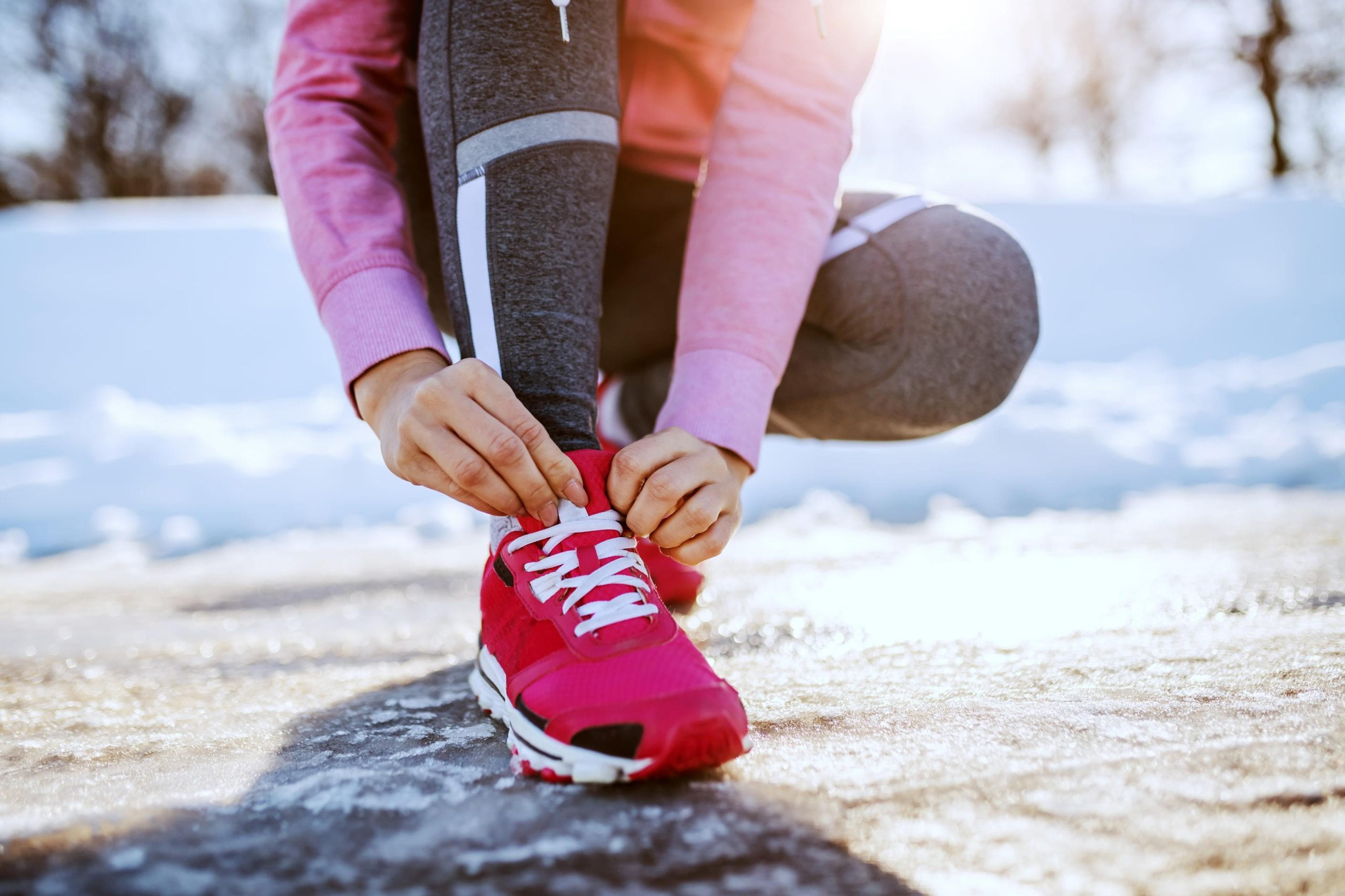 Woman lacing up her shoes to go for a winter run