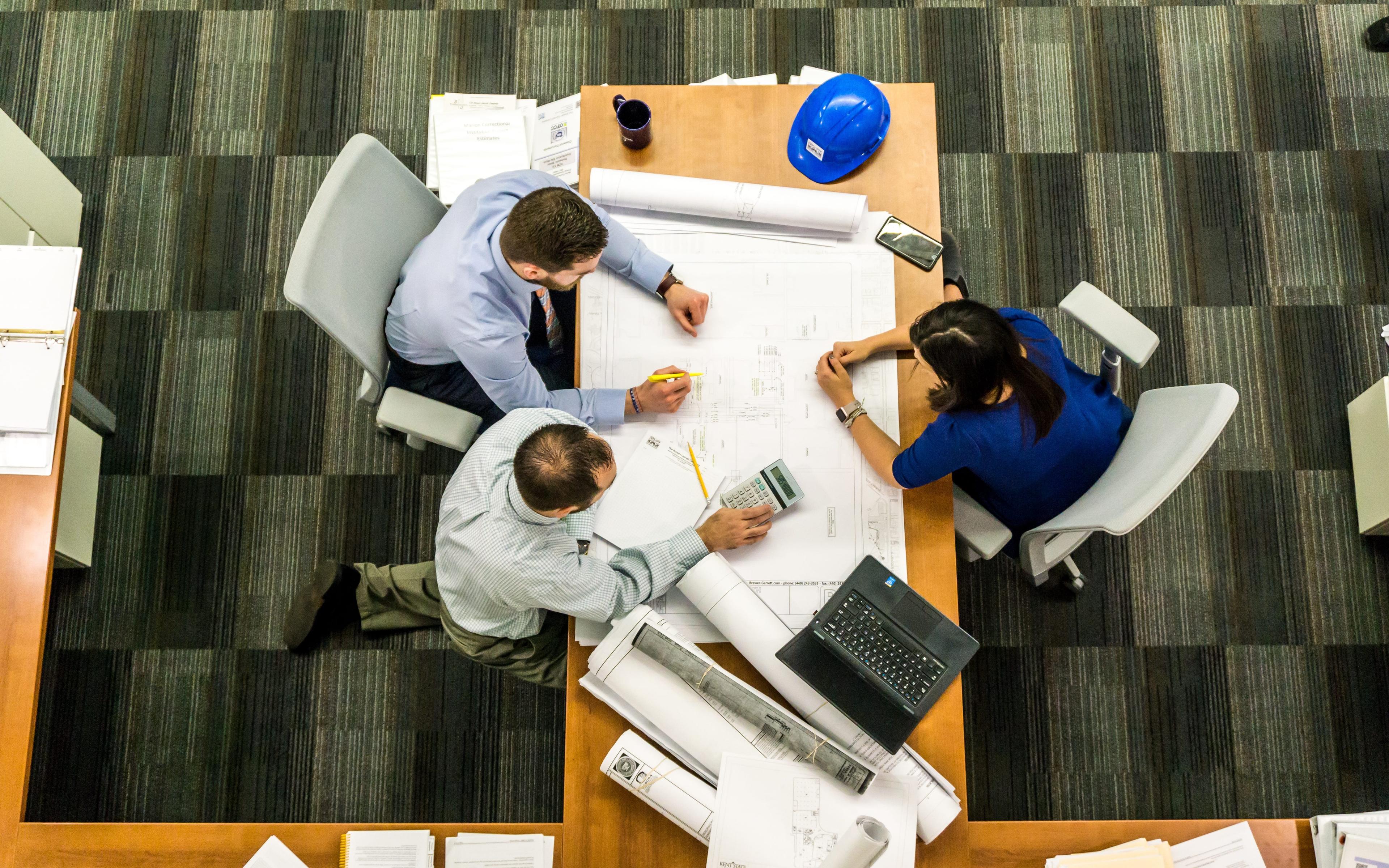 birds eye view of three people working at a table.