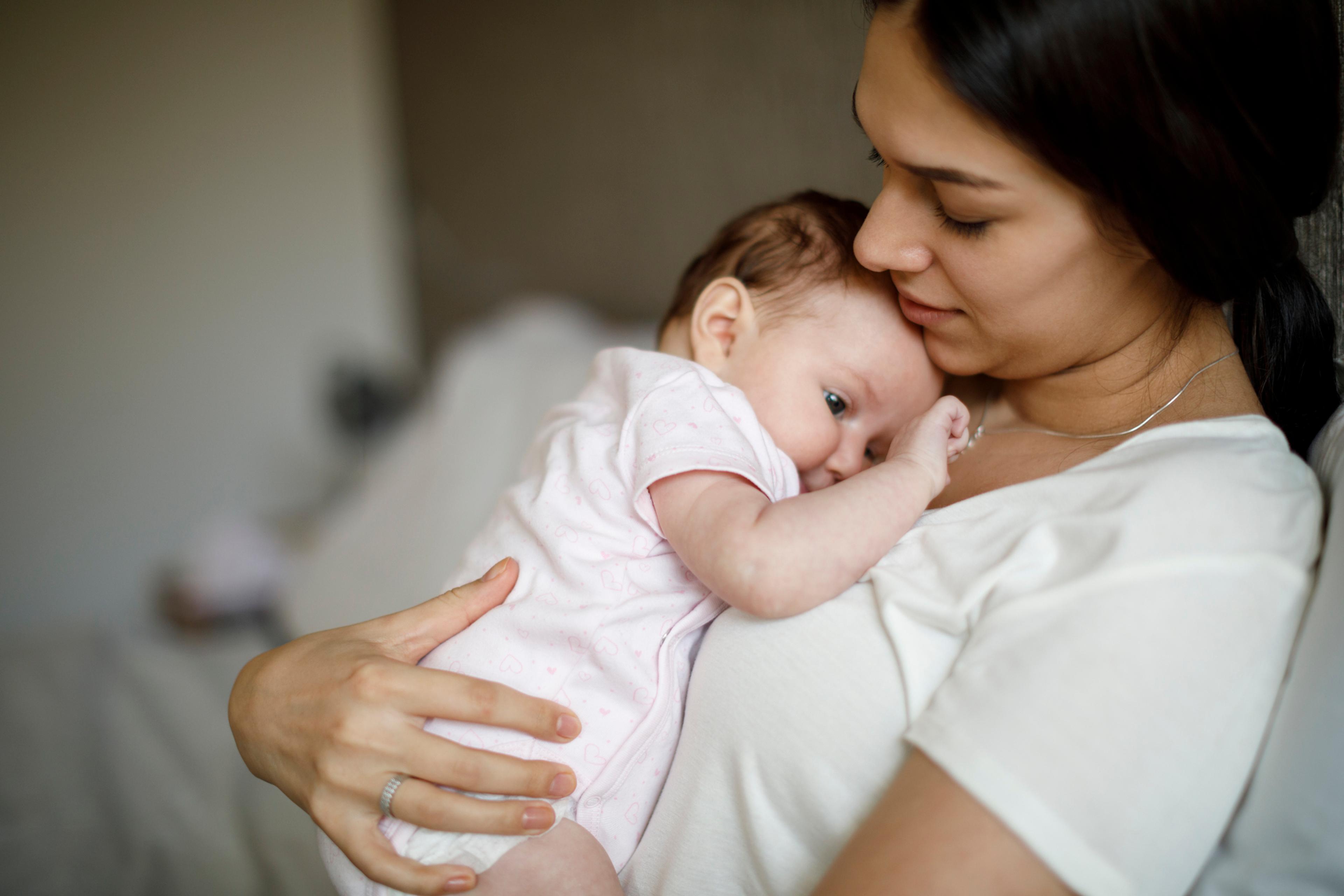 A young woman holds her infant.