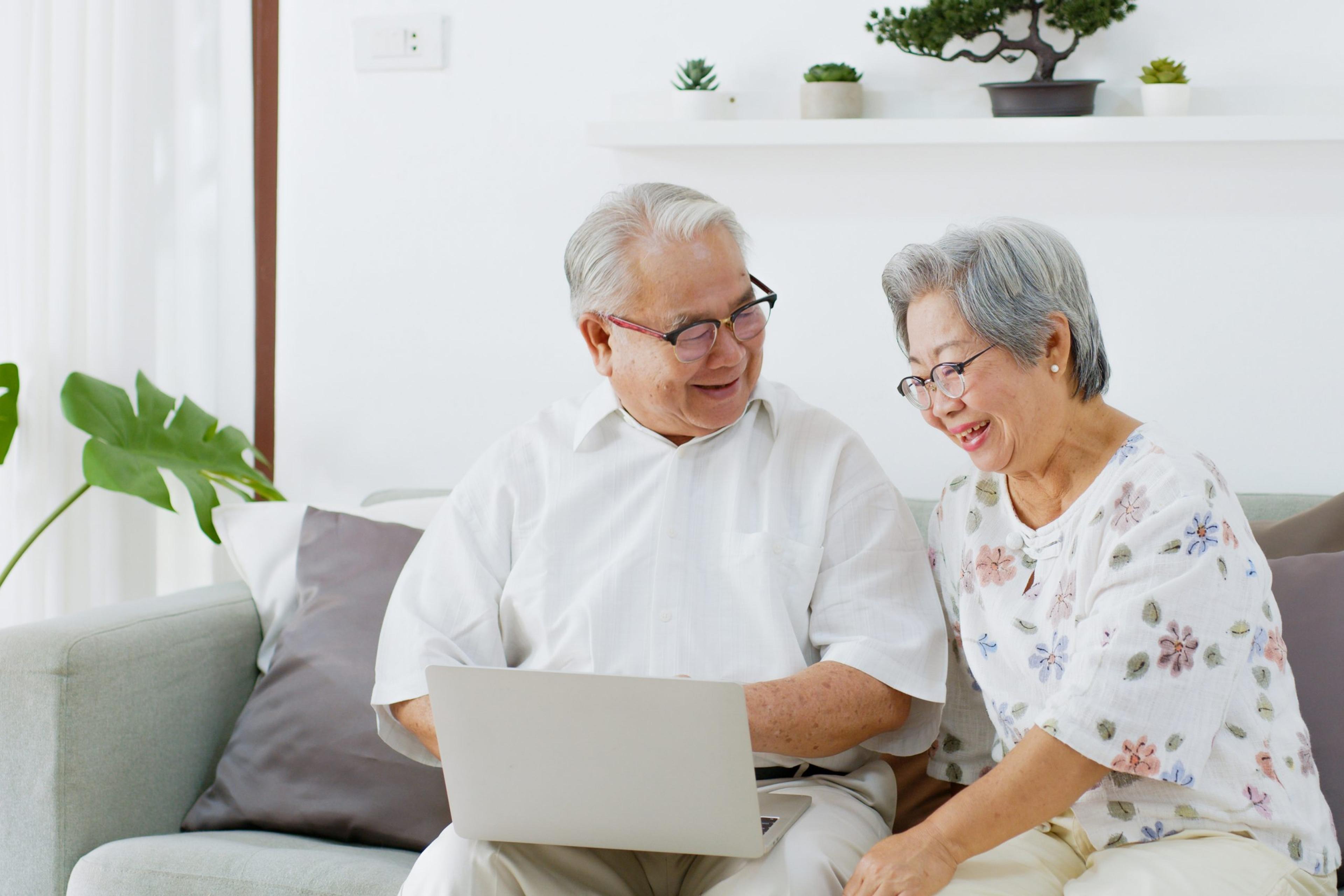 Asian senior couple using computer laptop to shop for Medicare Advantage plans online