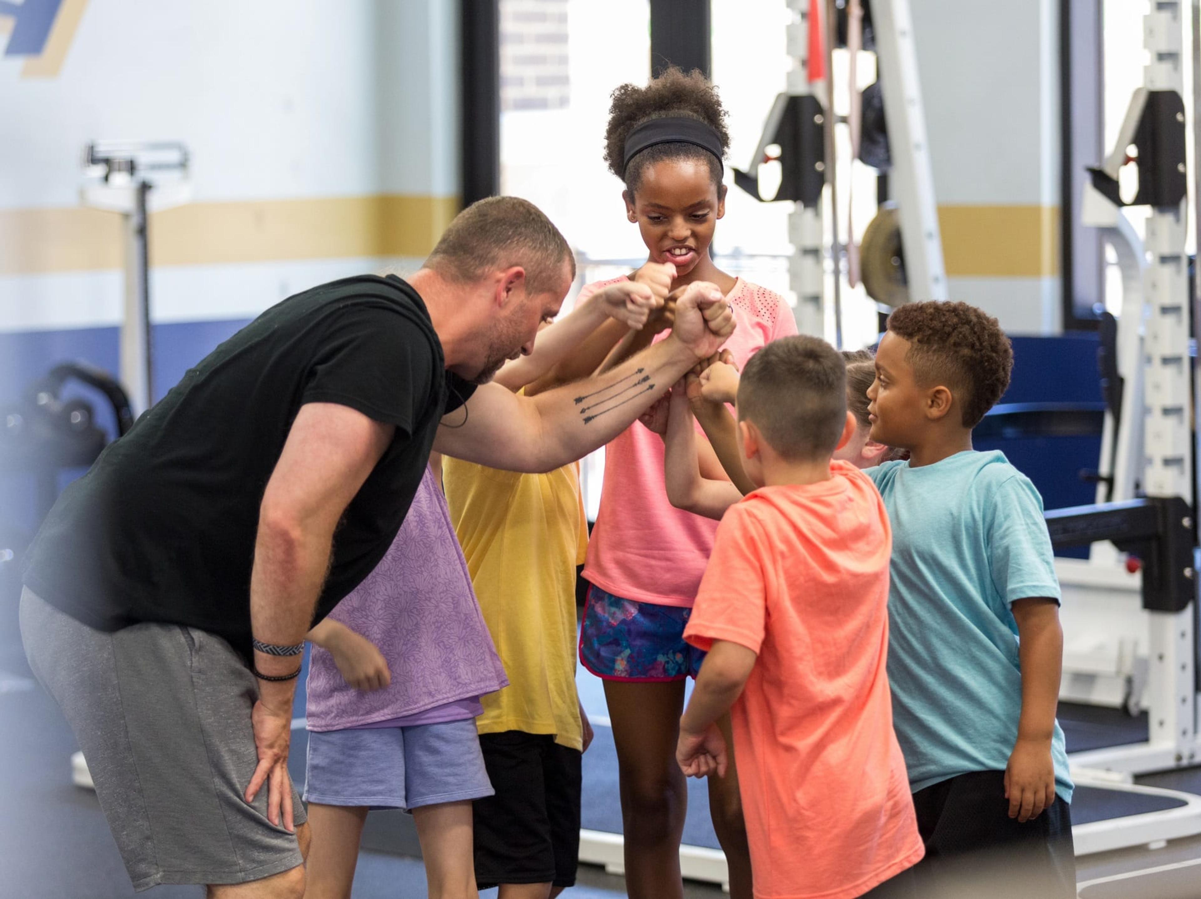 Fitness instructor encourages children in group exercise class