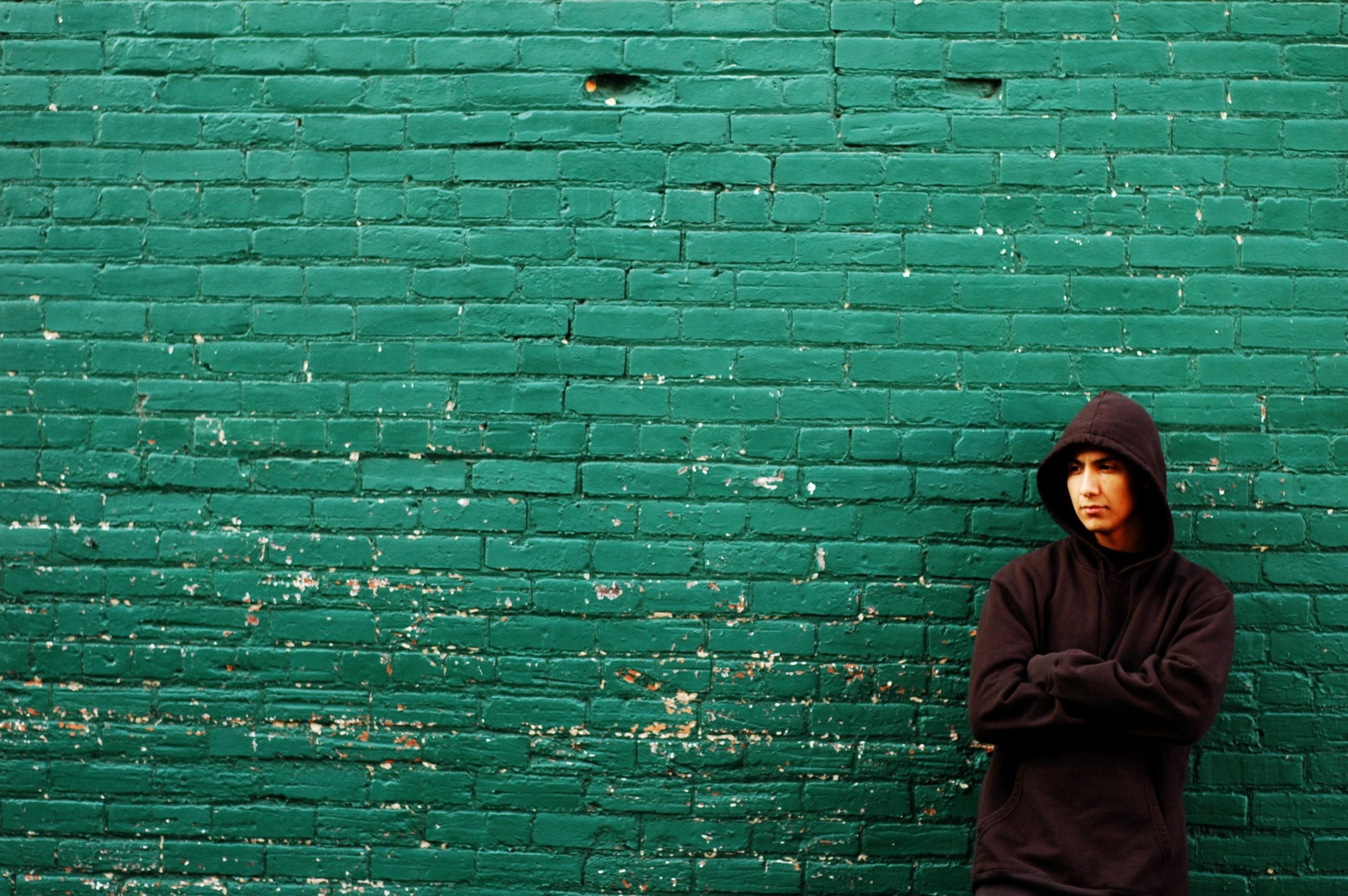 Image of a young man standing against a green wall.