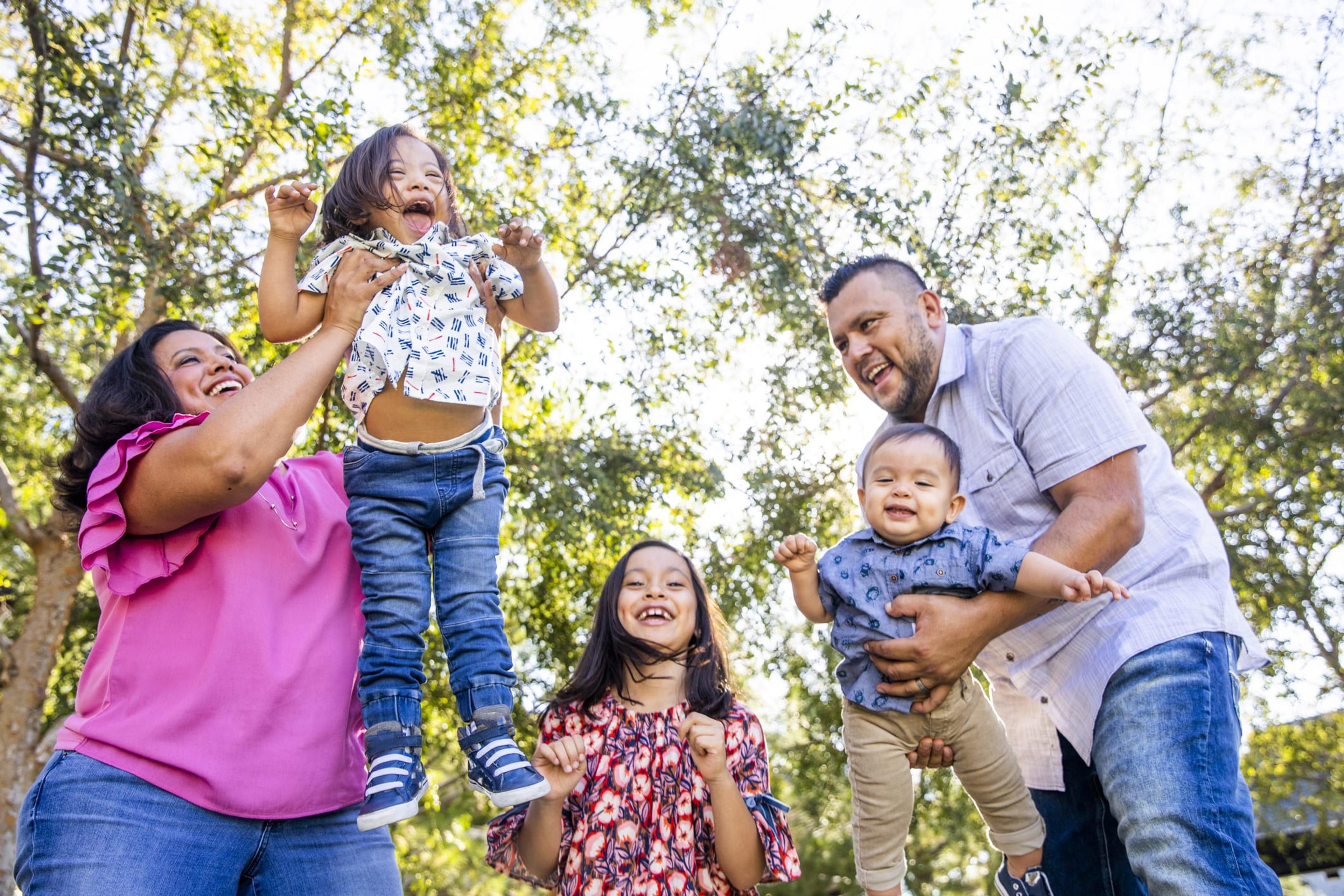 Hispanic family laughs and plays outdoors on a summer day.