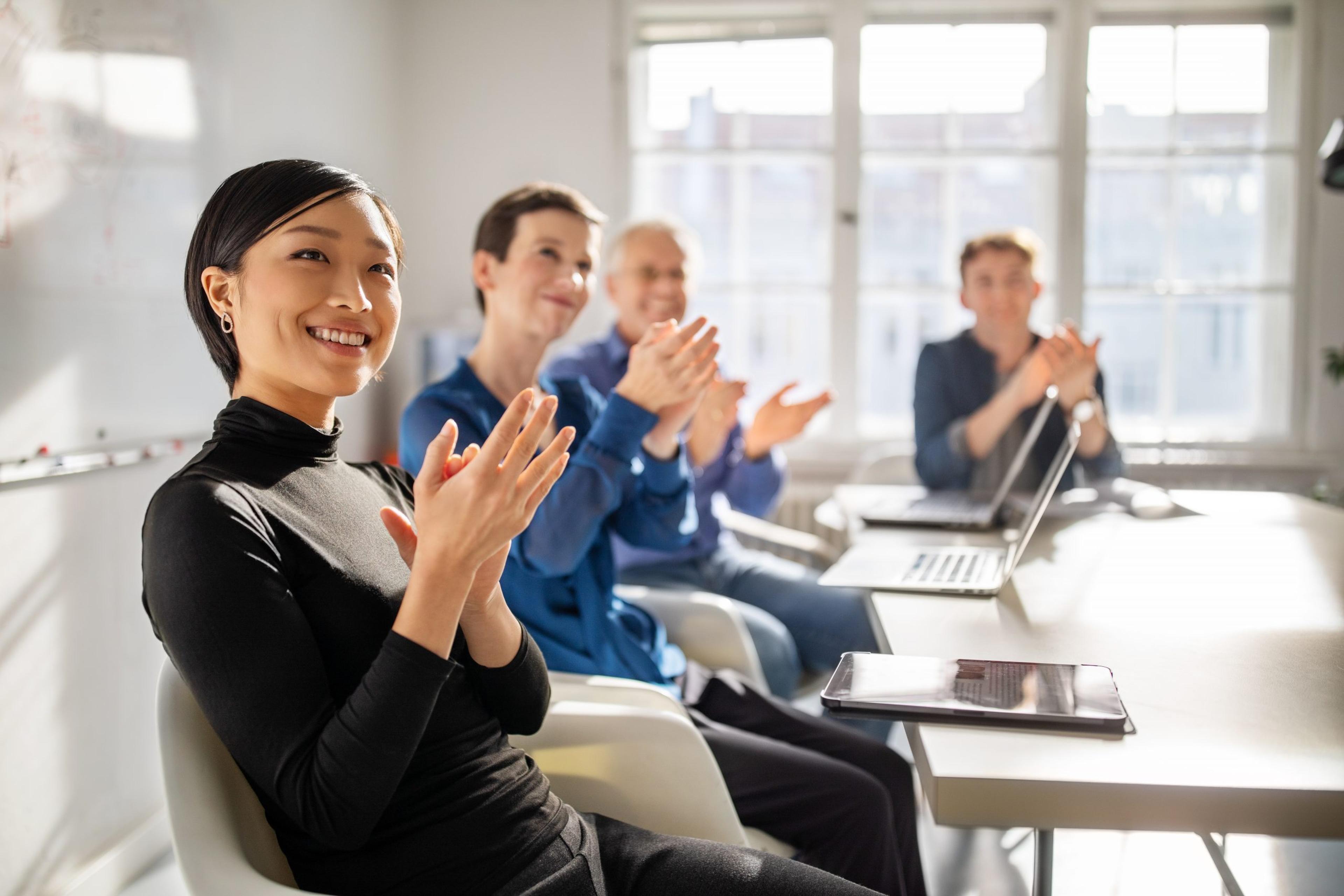 Business professionals clapping hands in a meeting