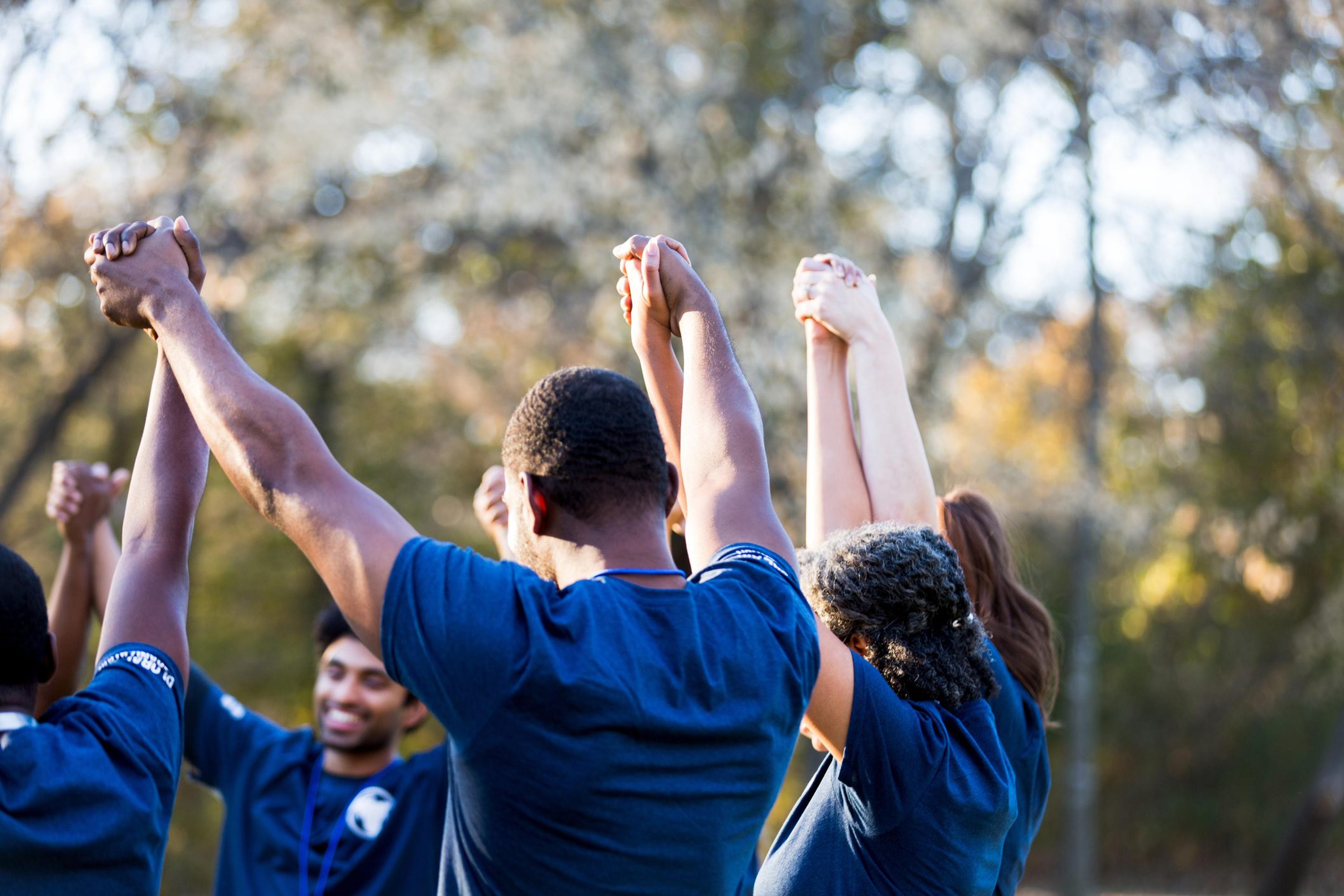 A group of people raise their hands in the air united.