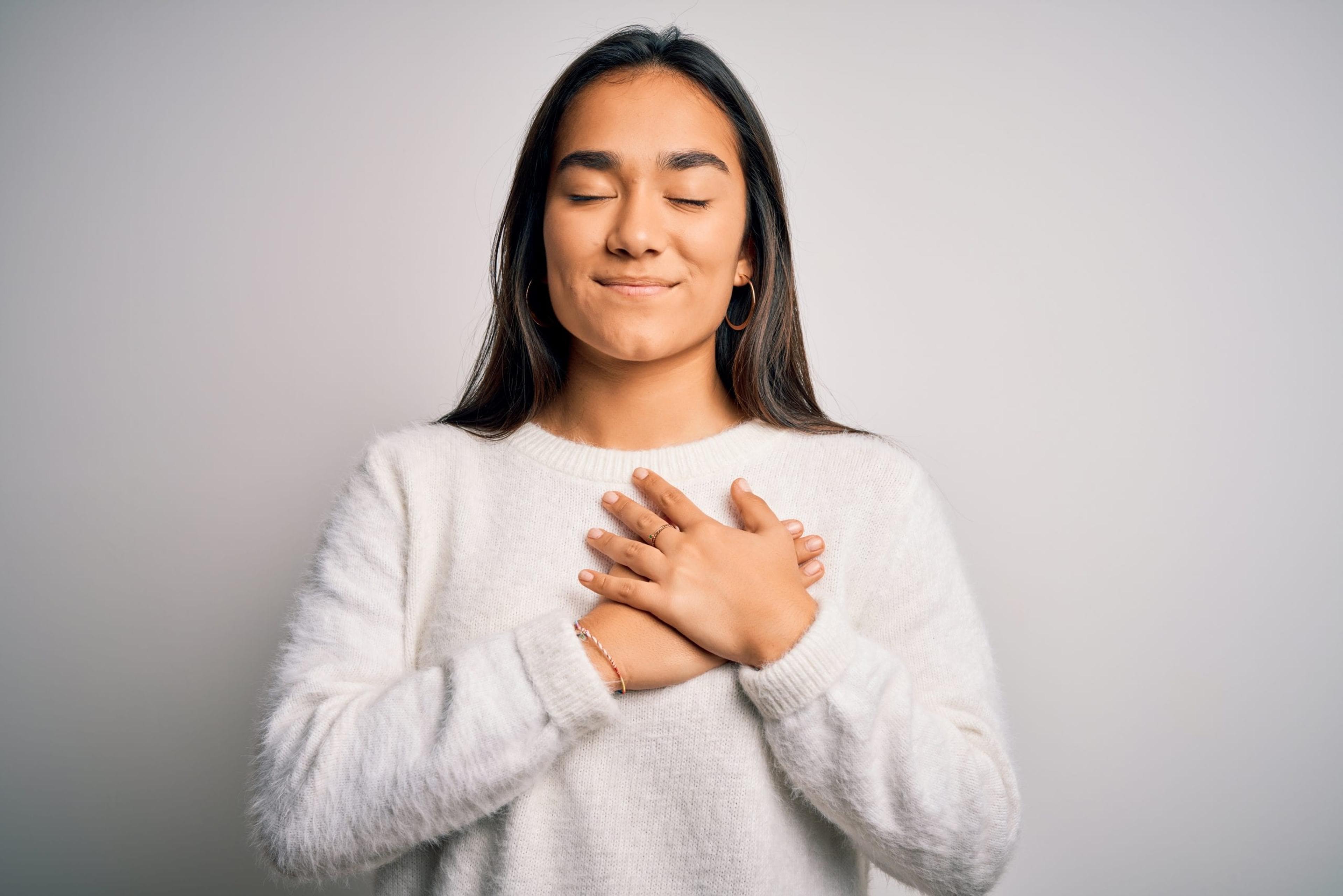 Woman holding heart with eyes closed