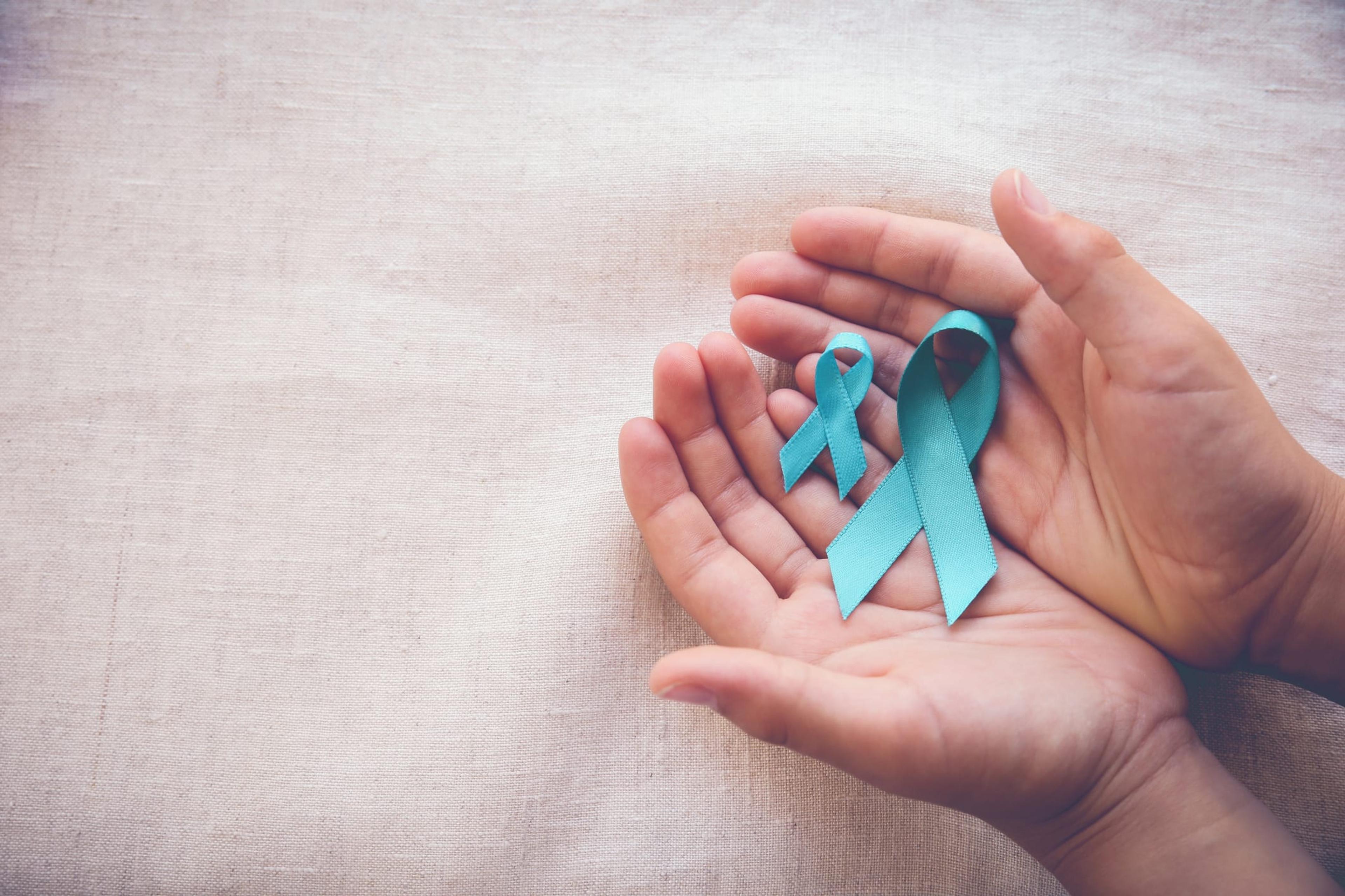 Hands holding teal ovarian cancer awareness ribbons