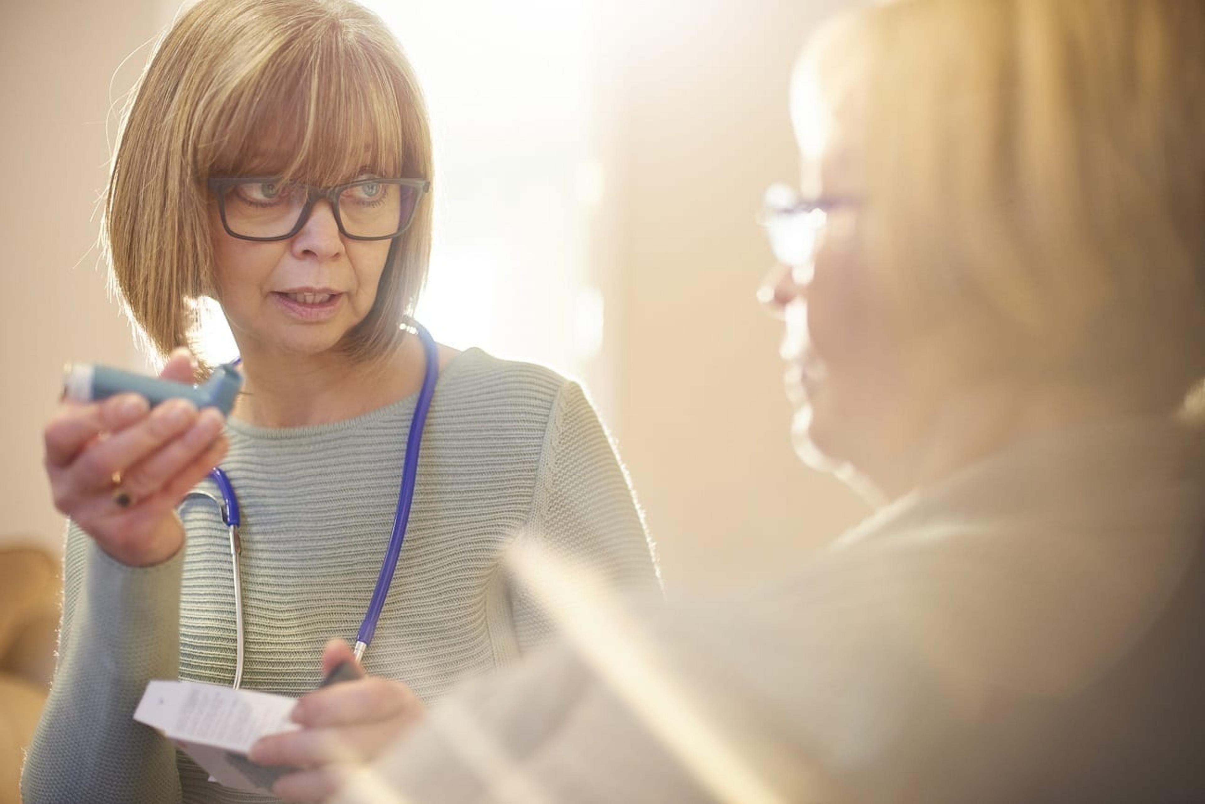 Female doctor instructs patient on asthma inhaler