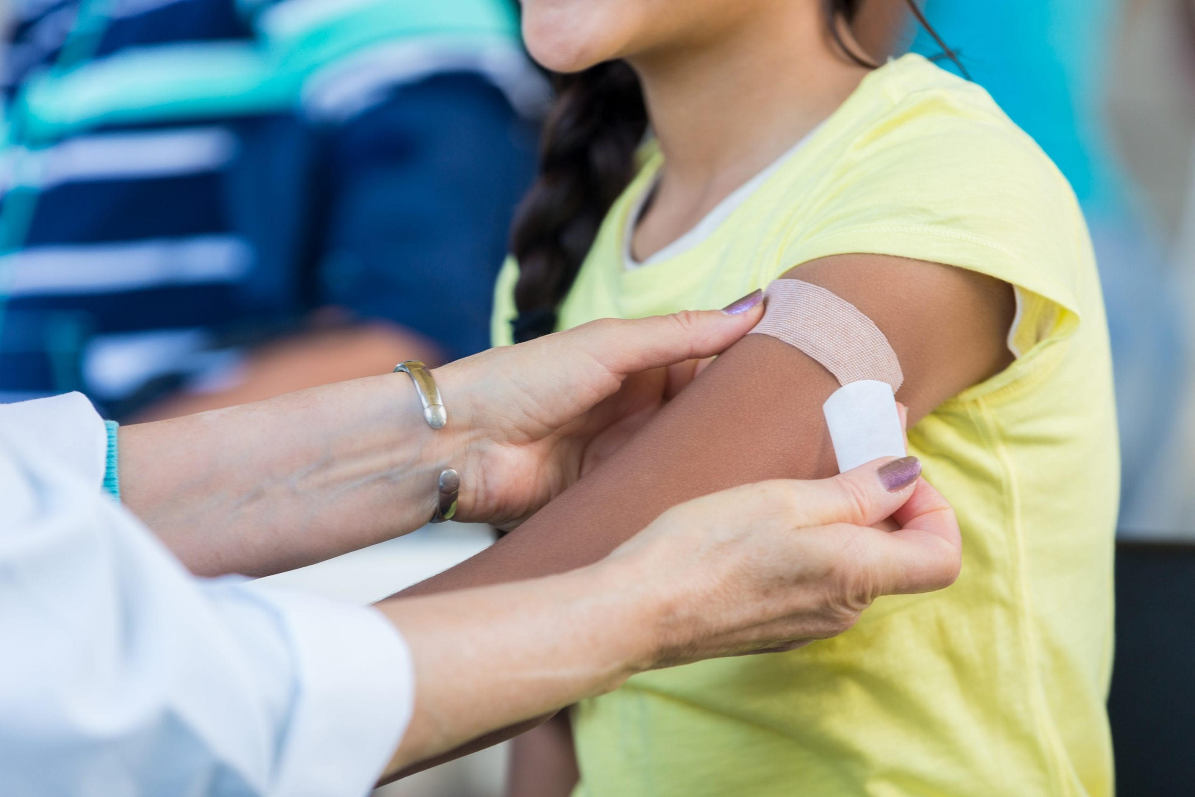 Bandage being placed on an arm after a flu shot.