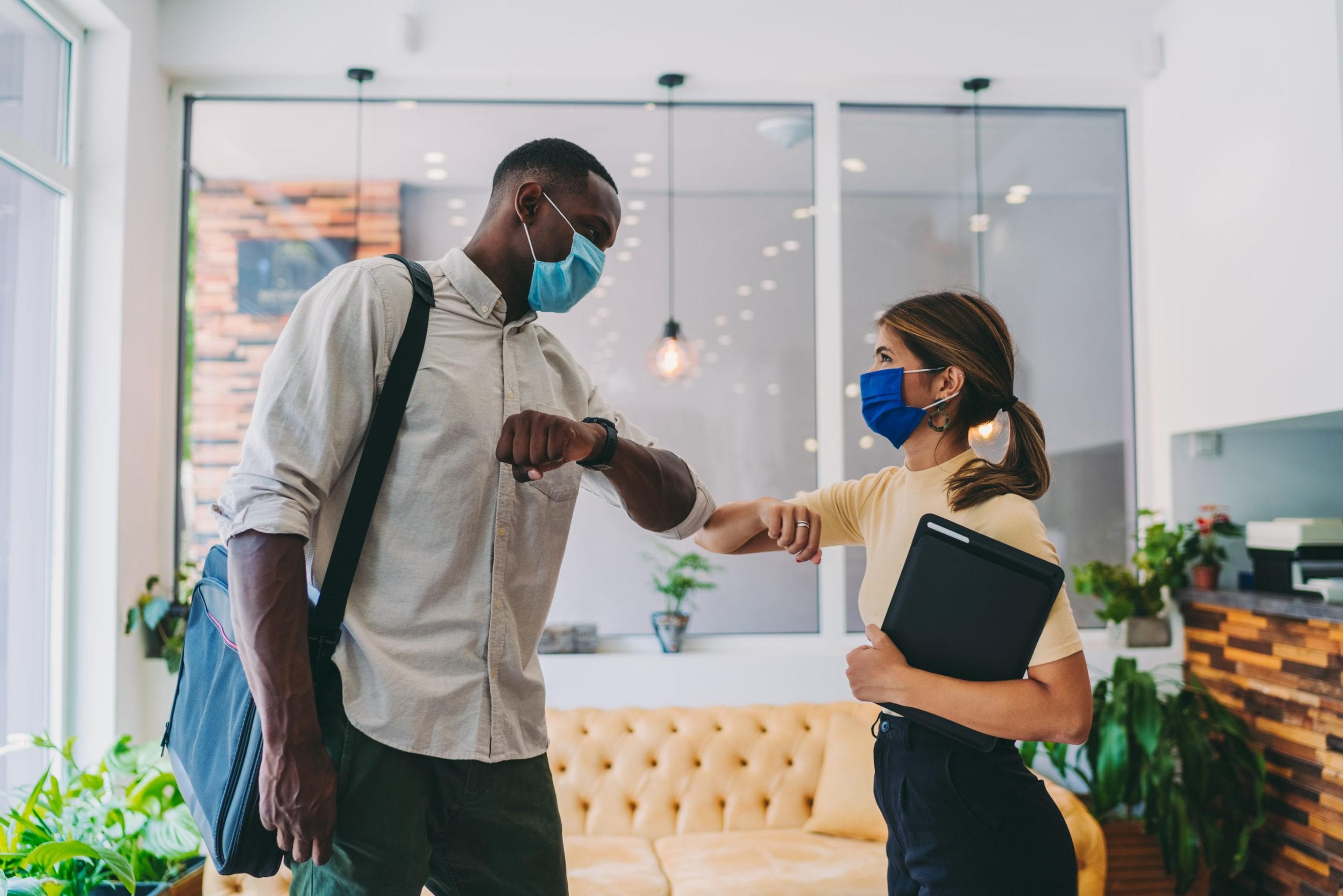 Co-workers elbow bumping with masks on